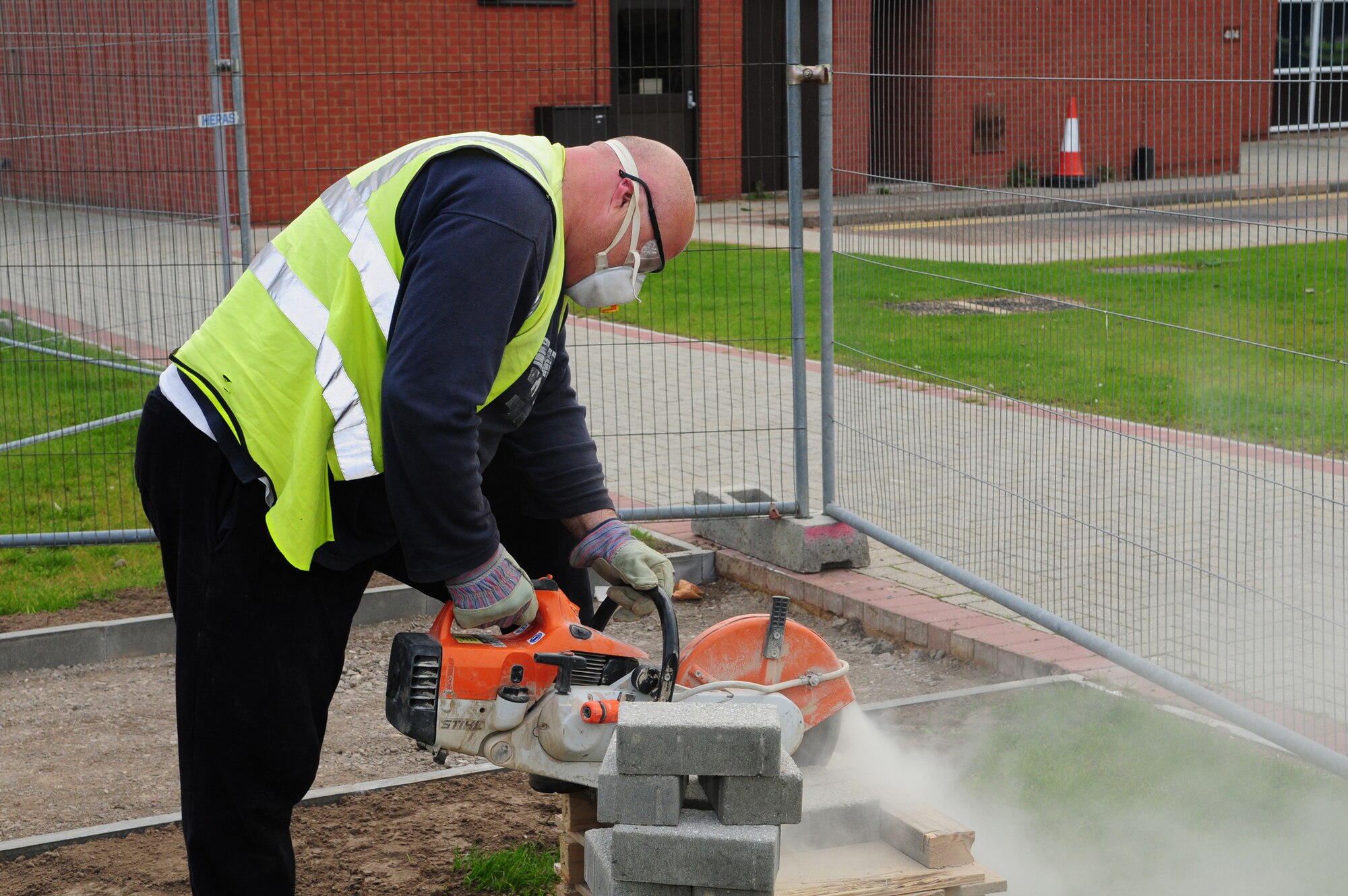 Phil Winder, 100th Civil Engineer Squadron, uses a K-12 block paving cutting machine to cut bricks for the pathway of Holiday Park. The new park is an area next to the Bob Hope Community Center which will centrally locate the annual holiday tree and cards display. In addition to the tree brought in annually in December, five live spruce trees will be permanently planted in the park area. Ten 100th CES personnel have been working on the area, which is estimated to be finished at the end of October. (U.S. Air Force photo by Karen Abeyasekere)