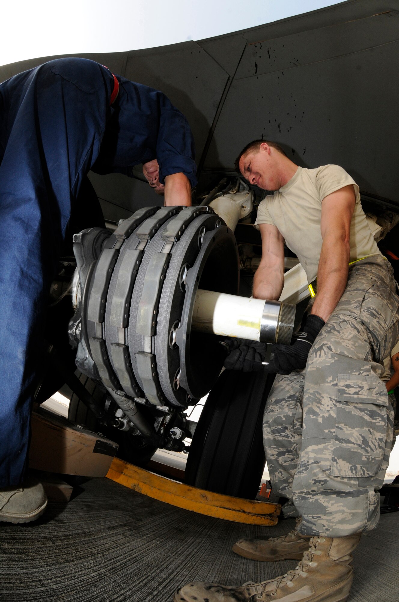 Airman 1st Class Ryan McMillen, on the rear of the tire, and Tech. Sgt. Chris Reiter, both assigned to the 379th Expeditionary Aircraft Maintenance Squadron, 340th Aircraft Maintenance Unit, muscle up to break loose the bolts holding an unserviceable brake unit on a KC-135 aircraft Sept. 28, 2008, at an undisclosed air base in Southwest Asia.  The brake set had to be replaced when a crack in the heat shield was detected during a post-flight inspection.  Sergeant Reiter, a native of Farmington, N.M., is deployed from Fairchild Air Force Base, Wash., and Airman McMillen, hailing from Warsaw, Ill., is deployed from McConnell AFB, Kan.  Both are deployed in support of Operations Iraqi and Enduring Freedom and Joint Task Force-Horn of Africa.  (U.S. Air Force photo by Tech. Sgt. Michael Boquette/Released)