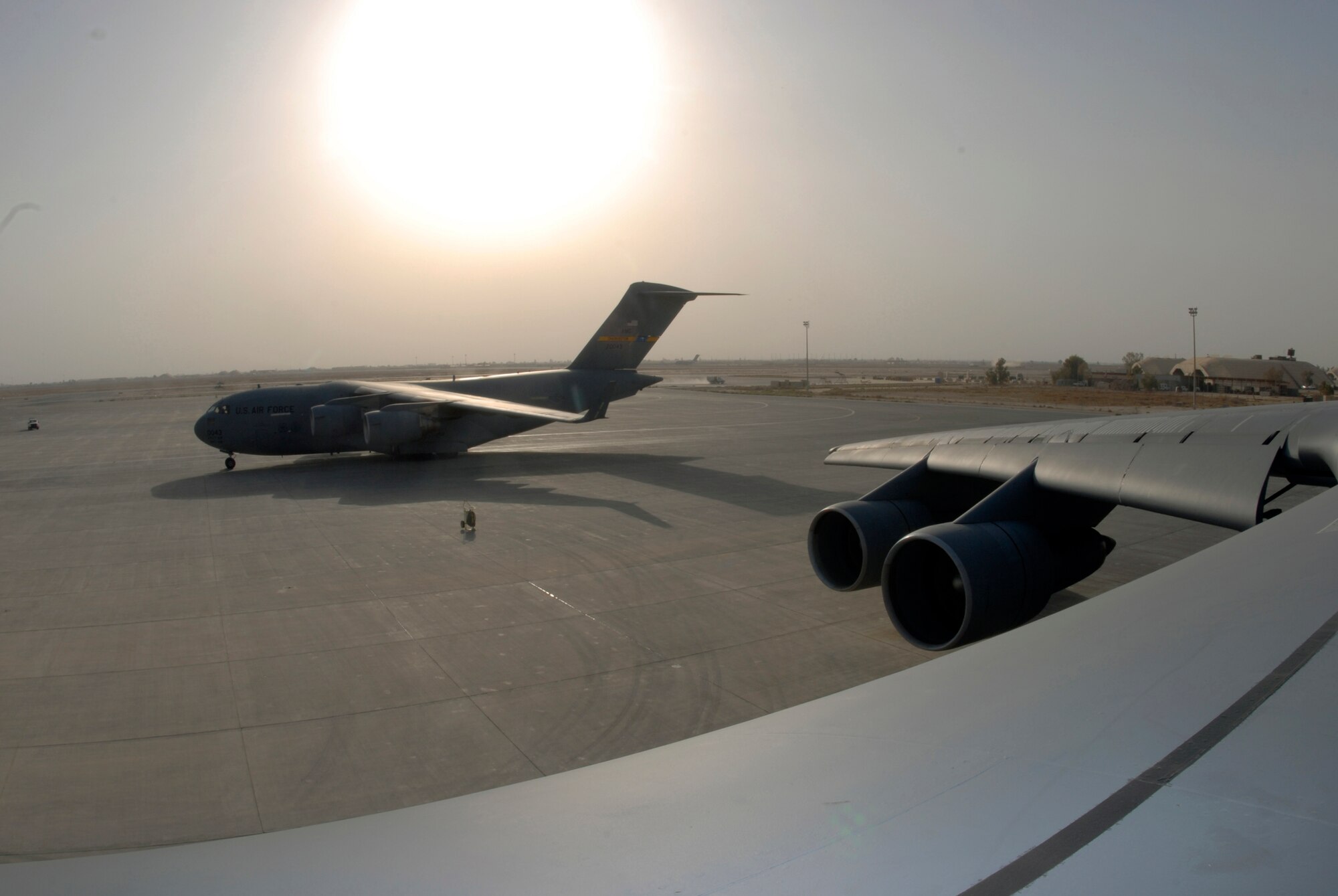 The sun shines on a C-5 Galaxy (foreground) and a C-17 Globemaster III at Joint Base Balad, Iraq, Sept. 26. The aerial port at Joint Base Balad is the busiest in the Department of Defense, moving more cargo per year than Dover Air Force Base, Del., Charleston AFB, S.C., and Travis AFB, Calif., combined. The C-5 is assigned to the 436th Airlift Wing at Dover AFB. The C-17 is deployed from the 437th Airlift Wing at Charleston AFB. (U.S. Air Force photo/Tech. Sgt. Erik Gudmundson) 