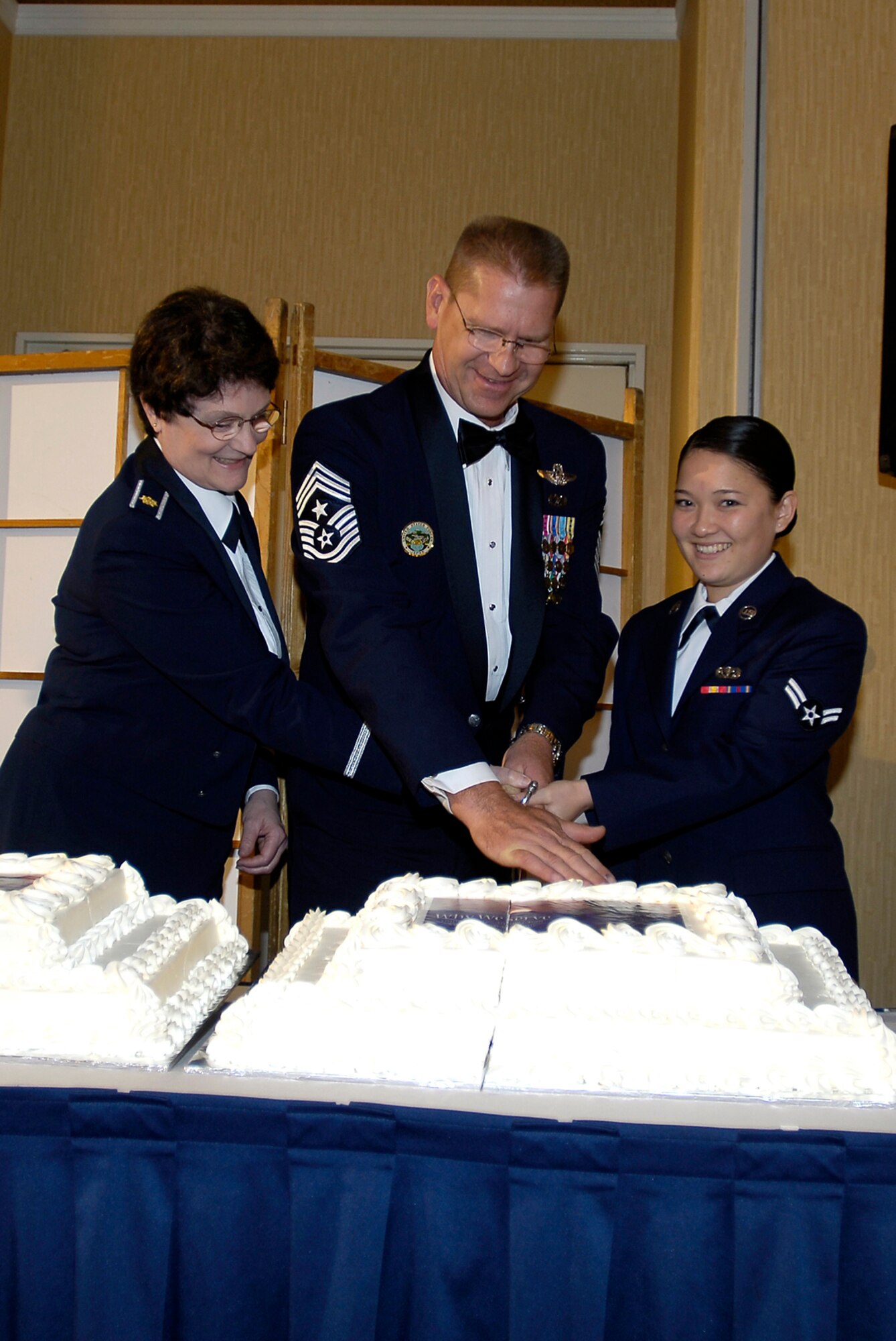 MISAWA AIR BASE, Japan -- Command Chief Master Sgt. Craig K. Deatherage, U.S. Forces Japan and 5th Air Force, flanked by Misawa Air Base's oldest and youngest Airmen, cut the cake during a cake-cutting ceremony at the Misawa Air Base's Air Force Ball Sept. 19, 2008. On the Chief's left was the base's oldest Airman, Maj. Pamela Darbyshire, 35th Surgical Operations Squadron Multi-Service Unit Flight commander. On his right was Misawa Air Base's youngest Airman, Airman 1st Class Letisha Paragas, 35th Force Support Squadron receptionist. (U.S. Air Force photo by Senior Airman Chad Strohmeyer)