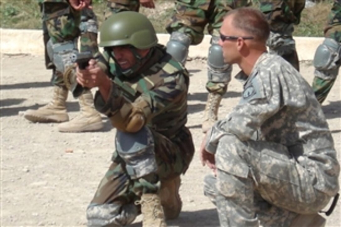 Sgt. Adam Zimmerman coaches Afghan National Army Staff Sgt. Assadullah Abdul Saleem on proper 9mm firing techniques during a weapons familiarization class at the Combined Security Transition Command, Afghanistan, Sept. 18, 2008.