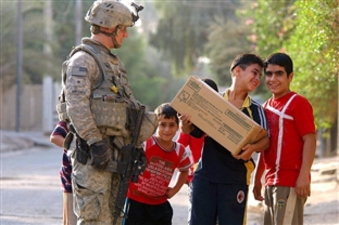 U.S. Army Spc. Brett Morando gives a box of food to a group of Iraqi boys while soldiers and Iraqi National Police patrolled the streets in Risalah, Baghdad, Iraq, Sept. 26, 2008. The soldiers are assigned to the 4th Brigade, 64th Calvary, 3rd Infantry Division. 
