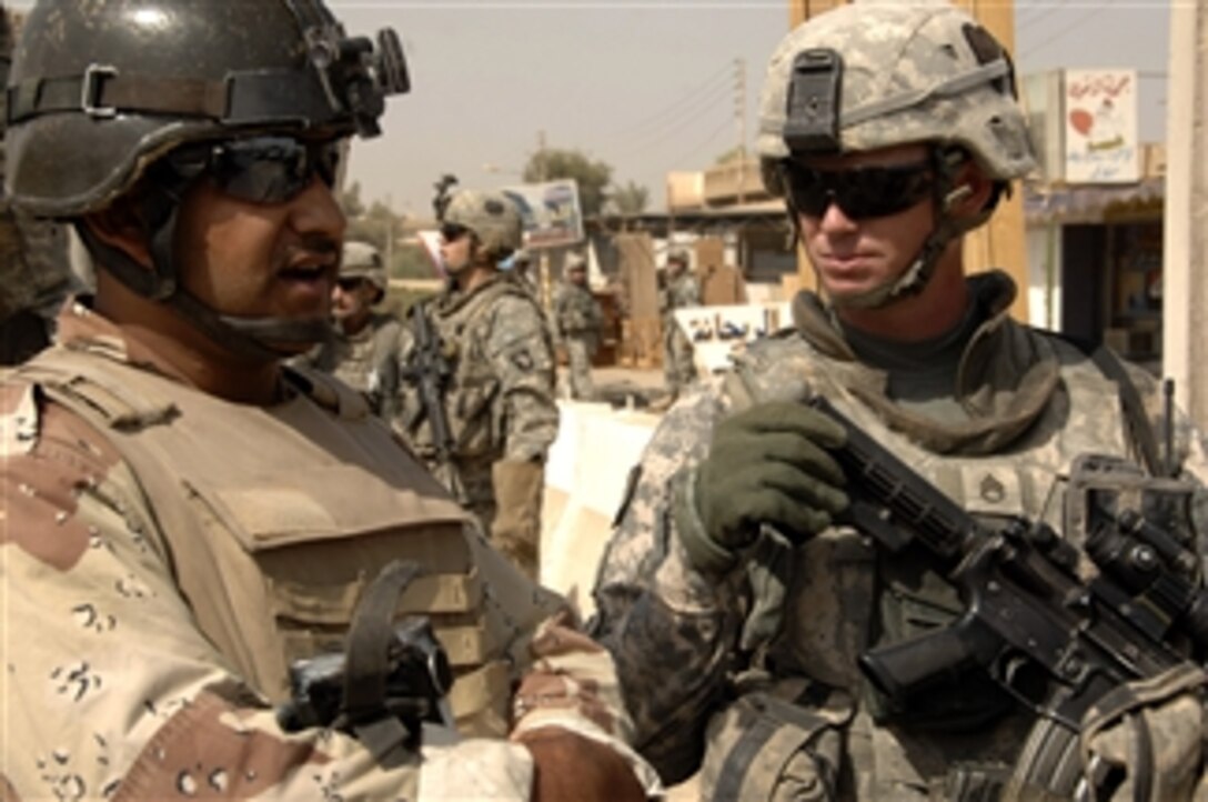 U.S. Army Staff Sgt. Jeremy Carney (right) speaks with an Iraqi soldier at a checkpoint during a patrol in the Gazaliyah district of Baghdad, Iraq, on Sept. 19, 2008.  Carney is assigned to Alpha Troop, 1st Squadron, 75th Cavalry Regiment, 2nd Brigade Combat Team, 101st Airborne Division.  