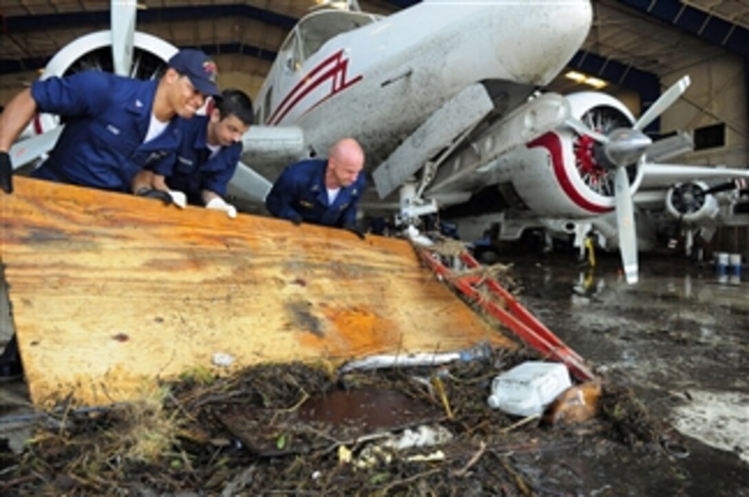 U.S. Navy Petty Officer 3rd Class Anthony Ford (left), Seaman Casey Johnson and Chief Warrant Officer Damian Schmitt, all assigned to the U.S. Navy amphibious assault ship USS Nassau (LHA 4), move sewage waste and debris from the Lone Star Flight Museum in Galveston, Texas, on Sept. 21, 2008.  The museum floor and antique airplanes were covered in sewage left behind by Hurricane Ike.  The Nassau is anchored off the coast of Galveston to provide humanitarian assistance support to civil authorities as directed in the wake of Hurricane Ike.  