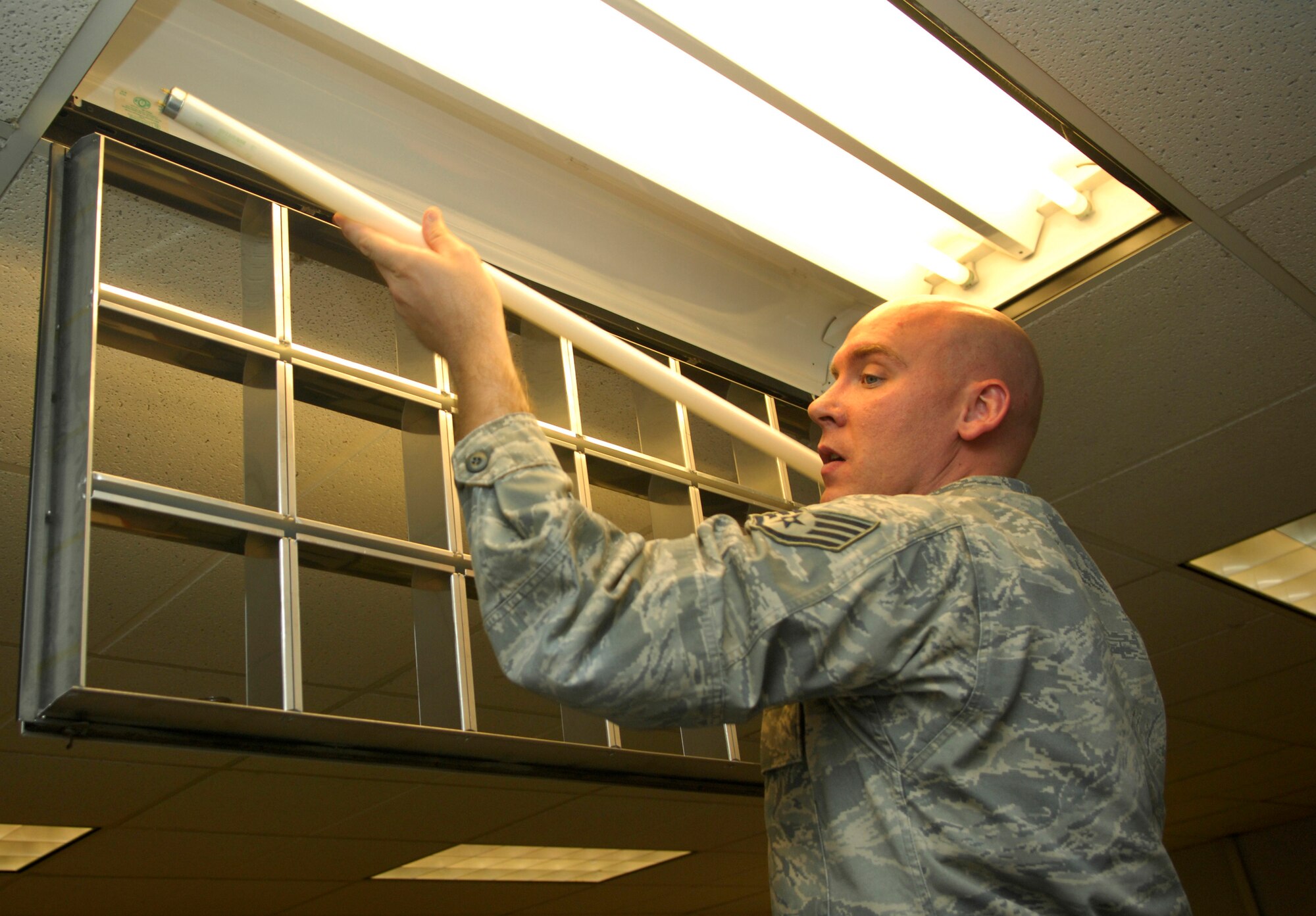 CANNON AIR FORCE BASE, N.M. -- Staff Sergeant James Killian, 27th Special Operations Comptroller Squadron and facility manager for Bldg. 600, installs a fluorescent light bulb during Energy Awareness Month. Several energy saving initiatives are under way to curb consumption and save the base approximately $129,000 annually. (U.S. Air Force photo/Senior Airman Erik Cardenas) 