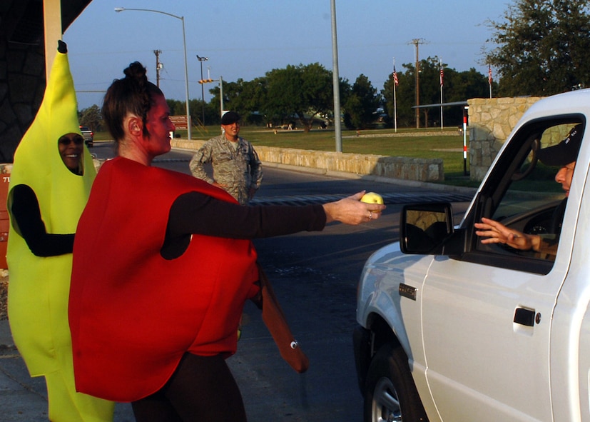 DYESS AIR FORCE BASE, Texas -- Amy Voyles-Brown and Patty McGruder, from Dyess’ Health and Wellness Center, hand fruit to servicemembers coming into Dyess’ front gate for National Fruit and Vegetable Month here, Sept. 24. HAWC members dressed up as fruit and gave fruit to everyone entering the front gate to encourage Airmen to maintain a healthy diet and eat seven to nine servings of fruits and vegetables daily. (U.S. Air Force photo/Senior Airman Felicia Juenke)