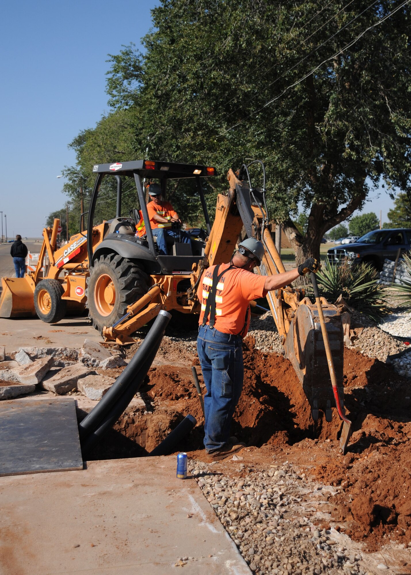 CANNON AIR FORCE BASE, N.M. -- Grounds man James Crun and machine operator Fernando Felix, from the General Dynamics Construction Company, work on adding more communication nodes to buildings in front of the Pecos Trail Dining Facility Sept. 30. This is just one of the three communication projects being accomplished on base. The others include the building of manhole duct systems and filling the ducts with additional cabling, allowing faster communication access. (U.S. Air Force photo/Airman Maynelinne De La Cruz)   