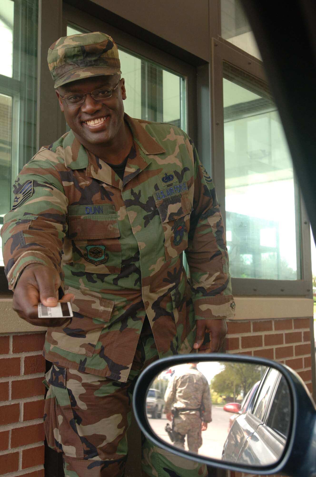 Tech. Sgt. Stefan Dunn, an Air Force Reservist from March AFB, Calif., on temporary duty as an augmentee with the 319th Security Forces Squadron, Grand Forks AFB, N.D. shows his locally famous dazzling smile as he returns an ID card during duty at the front gate.  The Bessemer, Ala. native sees duty here as a great opportunity to serve his country and has been recognized as one of the wing's best by the local community and wing leaders. (U.S. Air Force photo/Tech. Sgt. Joseph Kapinos)