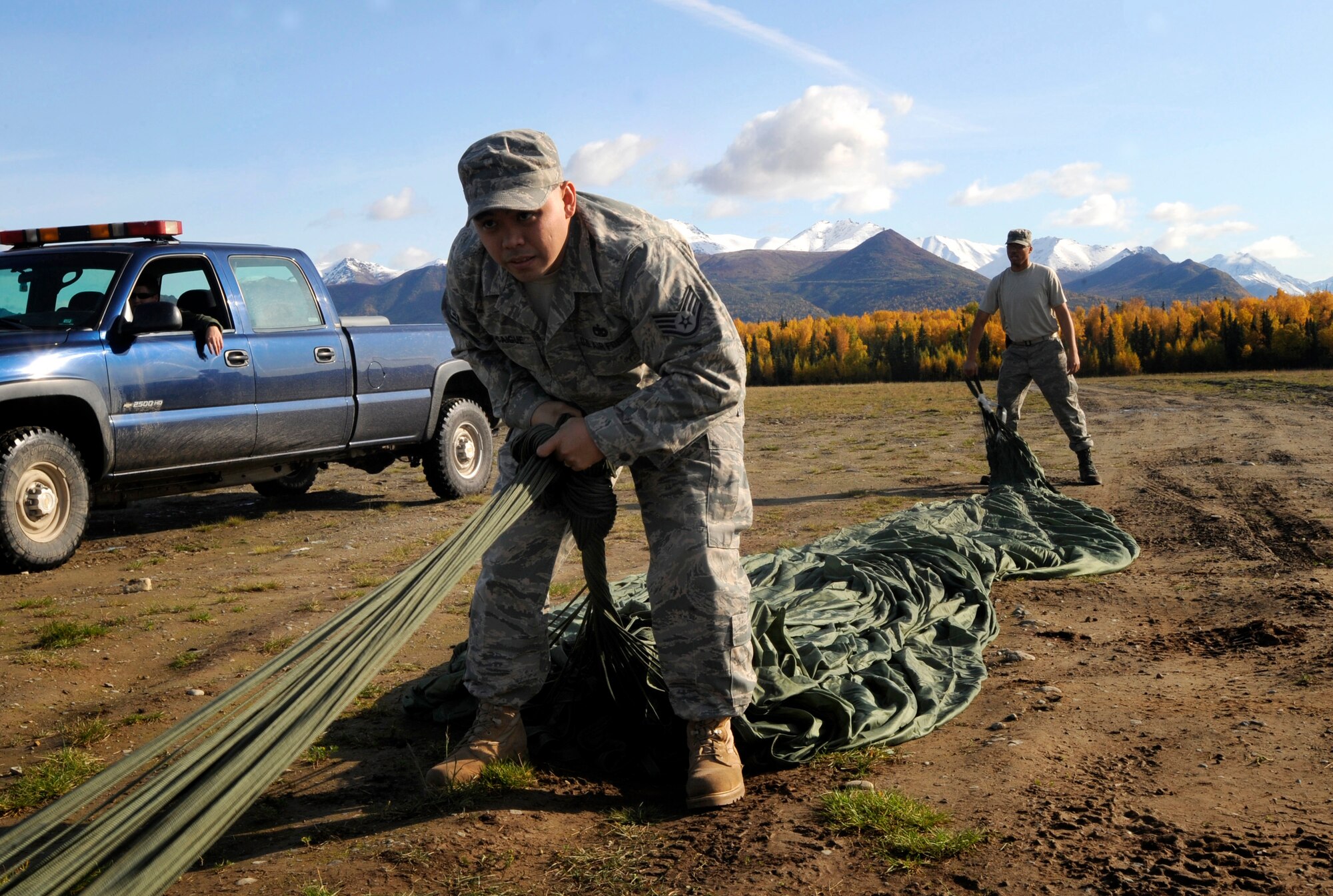 ELMENDORF AIR FORCE BASE, Alaska -- Staff Sgt. Aaron Pocaigue and Senior Airman Brandon Walker, 3rd Logistics Readiness Squadron, retrieve a parachute from an aerial delivery Sept. 26. The 3rd LRS uses these drops to prepare for aerial deliveries in wartime situations. (U.S. Air Force photo/Airman 1st Class Kristin High)