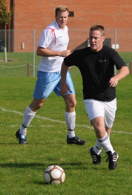 Scott Reed (in black) on the attack for the 100th FSS while Steven Alverson, (95th RS) looks on during the outdoor soccer championship at the Hardstand Sports field, Sept. 26. (U. S. Air Force photo by Staff Sgt. Jerry Fleshman)