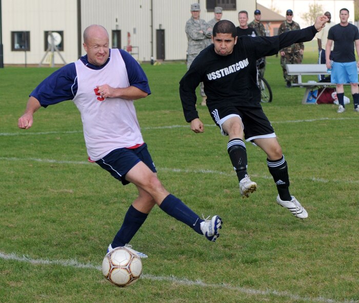 Greg Posada (in black) blasts a shot goalwards for the 100th FSS while Eric Evers from the 95th RS, tries to block, during the outdoor soccer championship at the Hardstand Sports field, Sept. 26. (U. S. Air Force photo by Staff Sgt. Jerry Fleshman)