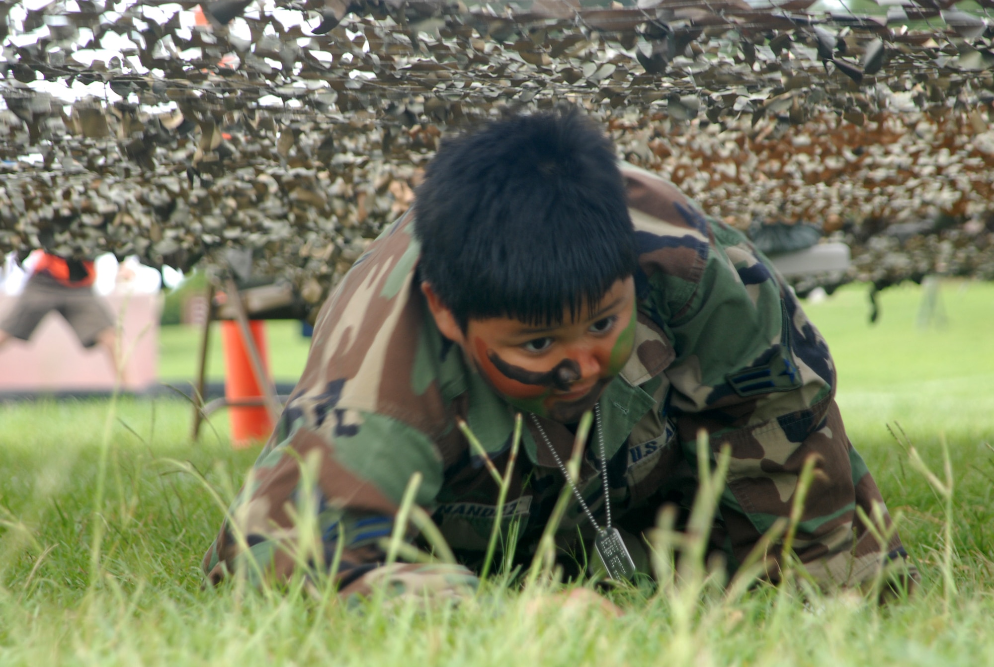 Nathan Fernandez, 9, son of Emelou and Staff Sgt. Fred Fernandez, 18th Communications Squadron, low crawls his way through the Skoshi Warrior obstacle course at Marek Park Sept. 27. The Airman and Family Readiness Center-sponsored event was designed to show children of deploying or deployed servicemembers what their parents experience before and during a deployment. (U.S. Air Force official photo/Staff Sgt. Nestor Cruz)