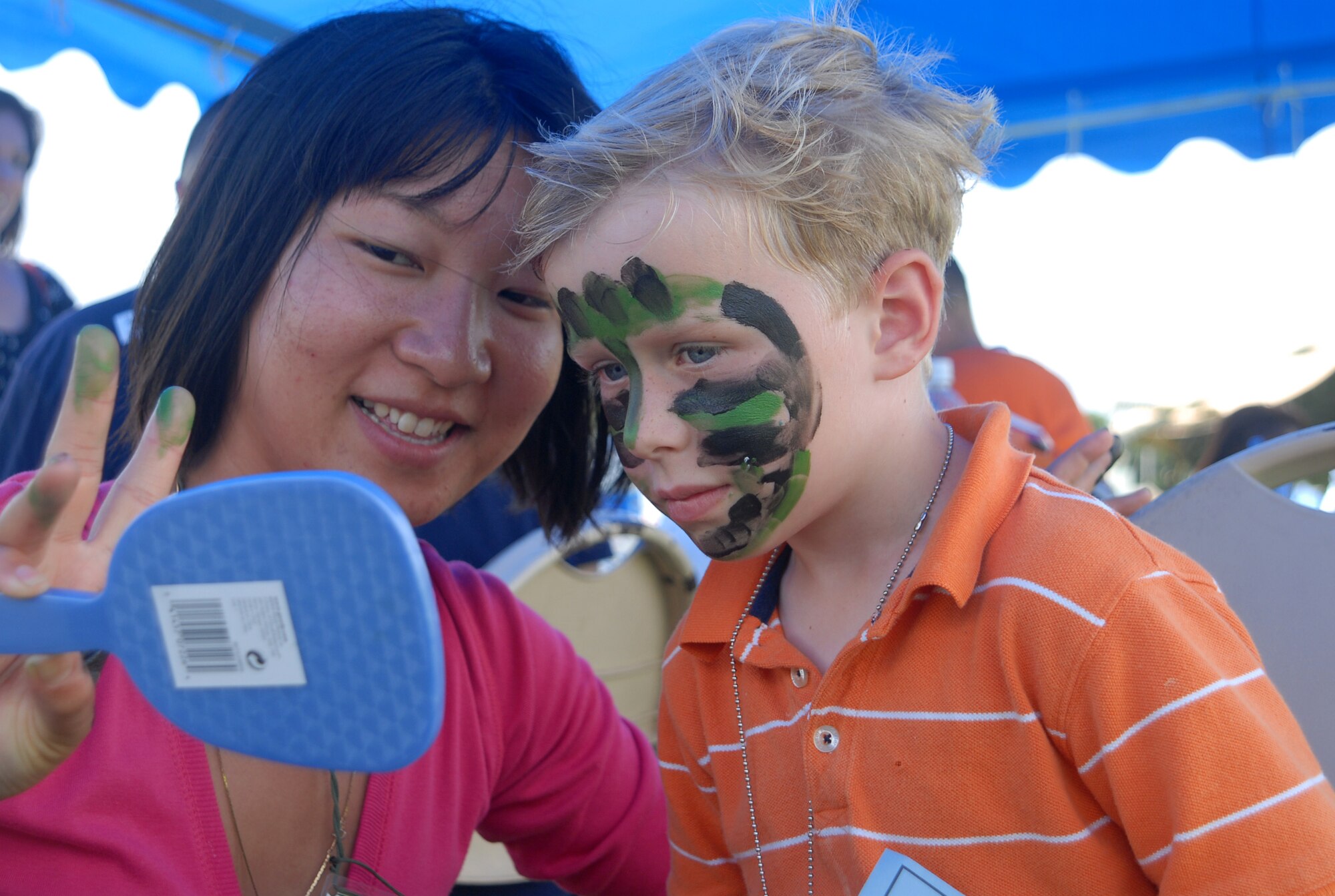 Hatsumi Ishibashi, a Skoshi Warrior volunteer, shows her handiwork to Thomas Carson, son of Barb and Lt. Col. Stephen Carson, 961st Airborne Air Control Squadron, at the face painting booth Sept. 27 during this year's Skoshi Warrior at Marek Park. The Airman and Family Readiness Center-sponsored event was designed to show children of deploying or deployed servicemembers what their parents experience before and during a deployment. (U.S. Air Force official photo/Staff Sgt. Nestor Cruz)