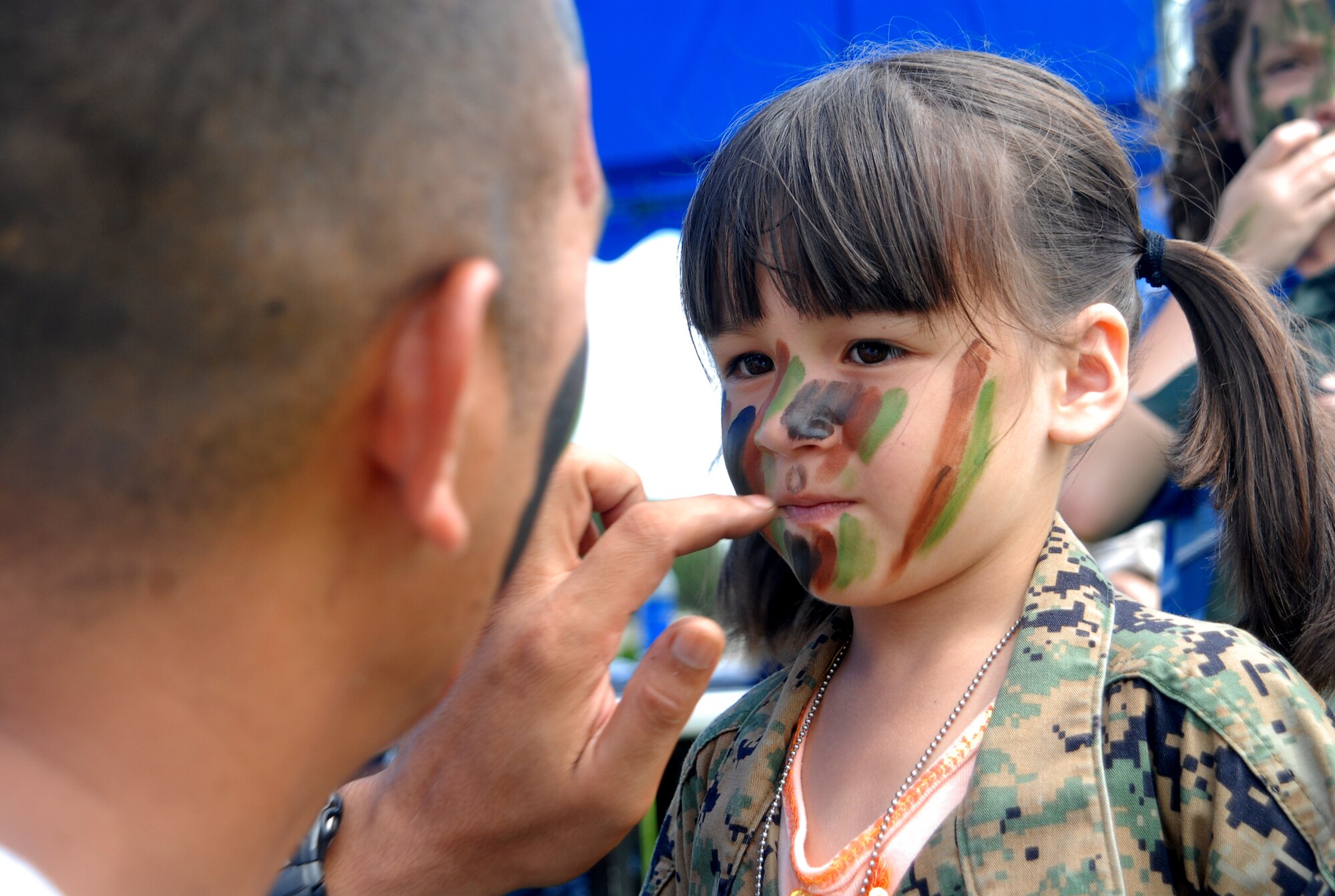 Master Sgt. Steven Harshman, 961st Airborne Air Control Squadron, applies the finishing touches on Shion Rudolph, 5, daughter of Marine Gunnery Sgt. Robert Rudolph, Marine Corps Station Futenma, at the face painting booth Sept. 27 during Skoshi Warrior at Marek Park. The Airman and Family Readiness Center-sponsored event was designed to show children of deploying or deployed servicemembers what their parents experience before and during a deployment. (U.S. Air Force official photo/Staff Sgt. Nestor Cruz)
