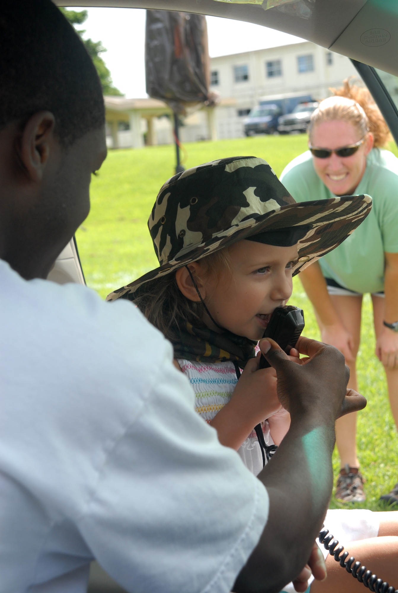 Autumn Stiens, 4, daughter of Beth and Army Capt. Chester Stiens, Special Forces 1-1, Torii Station, makes an impromptu announcementfrom an 18th Wing Security Forces squadron car as her mother looks on (background) Sept. 27 during Skoshi Warrior at Marek Park. The Airman and Family Readiness Center-sponsored event was designed to show children of deploying or deployed servicemembers what their parents experience before and during a deployment. (U.S. Air Force official photo/Staff Sgt. Nestor Cruz)
