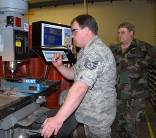 Master Sgt. Keith Bennett observes while Tech. Sgt. Sam Heinert operates the Computer Numeric Control (CSC) equipment in the machine shop.  (U.S. Air Force photo by Senior Master Sgt. Eric J. Peterson)