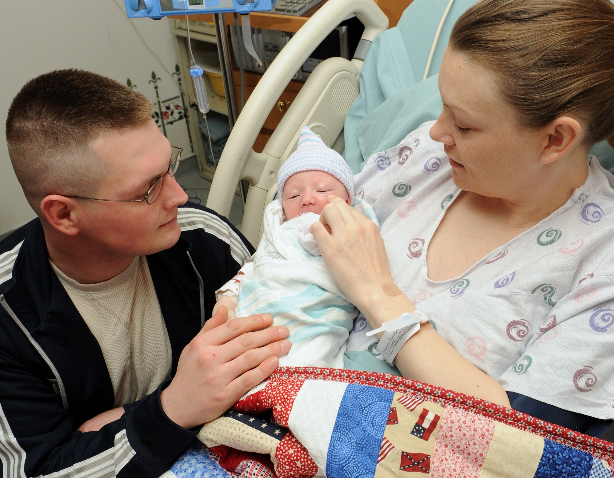 MOUNTAIN HOME AIR FORCE BASE, Idaho - New father Matthew Norwood smiles at his wife, Dena Norwood, and daughter, Kirsten Charolette Norwood, after receiving the 1,000th Hammond Baby Bundle at the base hospital March 24. Each baby bundle contains a handmade quilt and card made by base and local volunteers along with clothing, a stuffed animal and hat. Every baby born at the base hospital receives a bundle with each one numbered and tracked.  (U.S. Air Force photo by Airman 1st Class Debbie Lockhart)