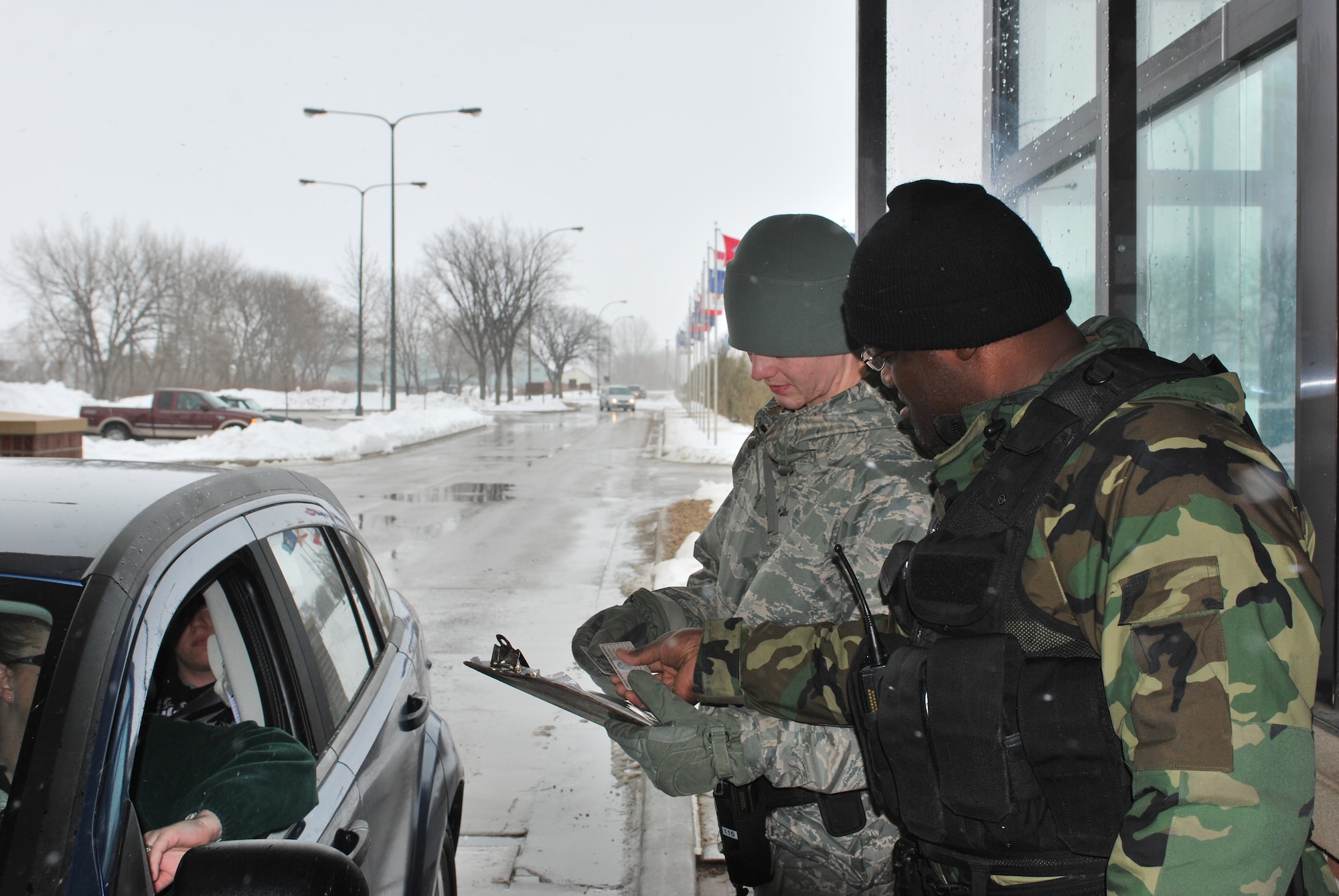 GRAND FORKS AIR FORCE BASE, N.D. -- Airman 1st Class Nathan Anderline (left), an Airman from the 5th Security Forces Squadron at Minot AFB, N.D., checks IDs the main gate here along with active duty Air National Guard member Tech. Sgt. Stefan Dunn. This is another example of Minot’s Airmen doing their part to help their fellow Airmen manage the high level of activity on the base due to the influx of servicemembers supporting the flood relief efforts along the Red River. (U.S. Air Force photo by Airman 1st Class Joshua Rosales)