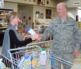 Staff Sgt. Thomas Bohl, NCO in charge of logistics at emergency management with the 71st Logistics Readiness Squadron, offers a free water bottle to a Vance commissary patron as part of the emergency supply kit demonstration Tuseday, March 31. (U.S. Air Force photo by 2nd Lt. Lynn Aird)