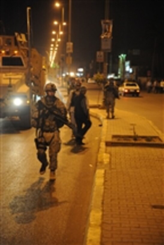 U.S. Army Staff Sgt. Anthony Grey from the 978th Military Police Company, 93rd Battalion, 8th Military Police Brigade patrols the street with Iraqi police officers in the Kadamiyah area of Baghdad, Iraq, on March 27, 2009.  