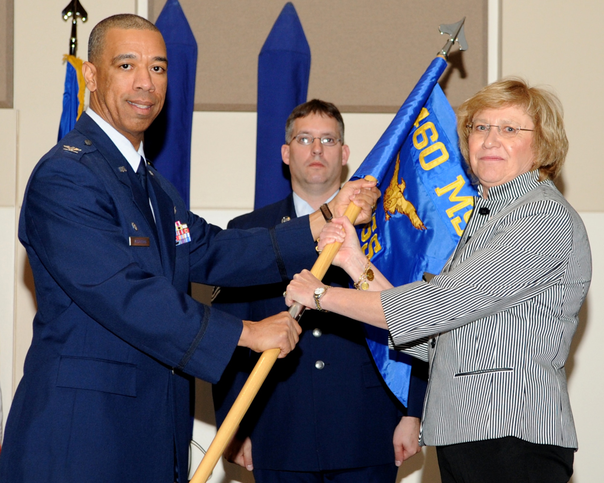 BUCKLEY AIR FORCE BASE, Colo. -- Col. Vincent Jefferson, 460th Mission Support Group Commander, hands the Force Support Squadron guidon to Birgit Baldwin, FSS Director, during the Squadron's stand up ceremony March 17 at the Leadership Development Center. The 460th Services Division has merged with the 460th MSS to form the 460th FSS. (U.S. Air Force photo by Senior Airman Erika Brooke)
