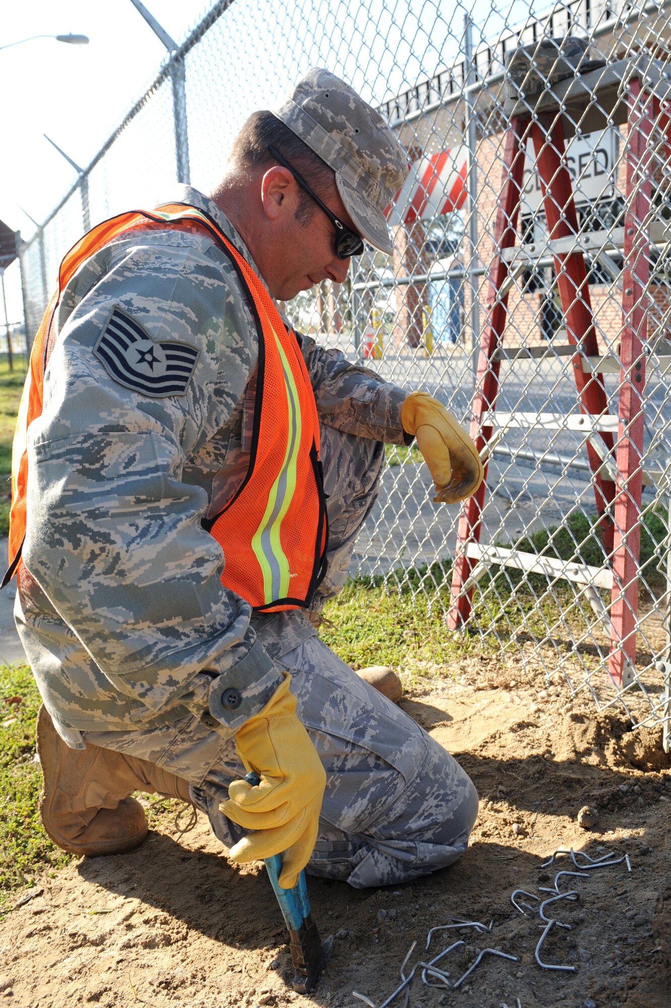 Technical Sgt. Robert Echols, a 567th Red Horse reservist, who is filling the void of 4th Civil Engineer Squadron’s deployed members, tightens a clamp at the bottom of a tension bar on the fence on Seymour Johnson Air Force Base, N.C., March 31, 2009. Tightening the tension bar holds the fence in place at Slocomb Gate. 4th CES Heavy Equipment Airmen do many of the outdoor jobs on this base such as fixing fences. (U.S. Air Force photo by Airman 1st Class Whitney S. Lambert)  