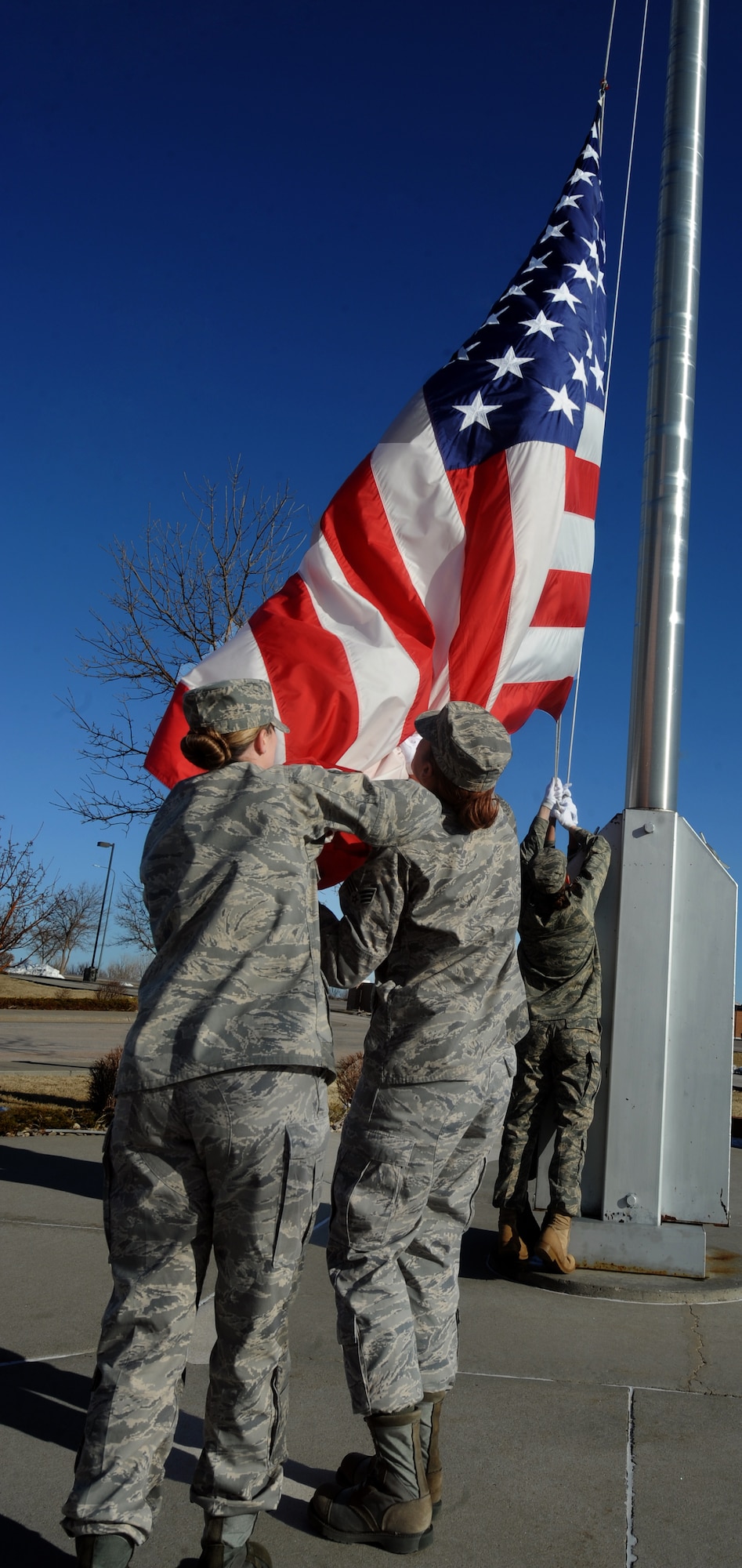 (Left) Staff Sgt. Patricia Lock, 28th Bomb Wing Command Chief executive assistant, assists Senior Airman Jacquelyn McFalls, Air Force Financial Service Center reserve travel technician, to lower the flag during a retreat honoring women, which took place here, Mar. 27. The retreat performed by an all-female flight symbolizing the impact women on the military whether flying combat missions, commanding Airmen, or supporting daily combat operations around the world. (U.S. Air Force photo by Airman First Class Adam Grant)	
