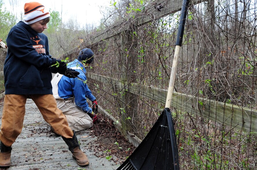 Trail restoration volunteers remove overgrown vines from a bridge along the Big Tree Hiking Trail. The bridge is over 580 feet long and weaves through swamp areas along the trail. (U.S. Air Force photo by Senior Airman Joanna M. Kresge)