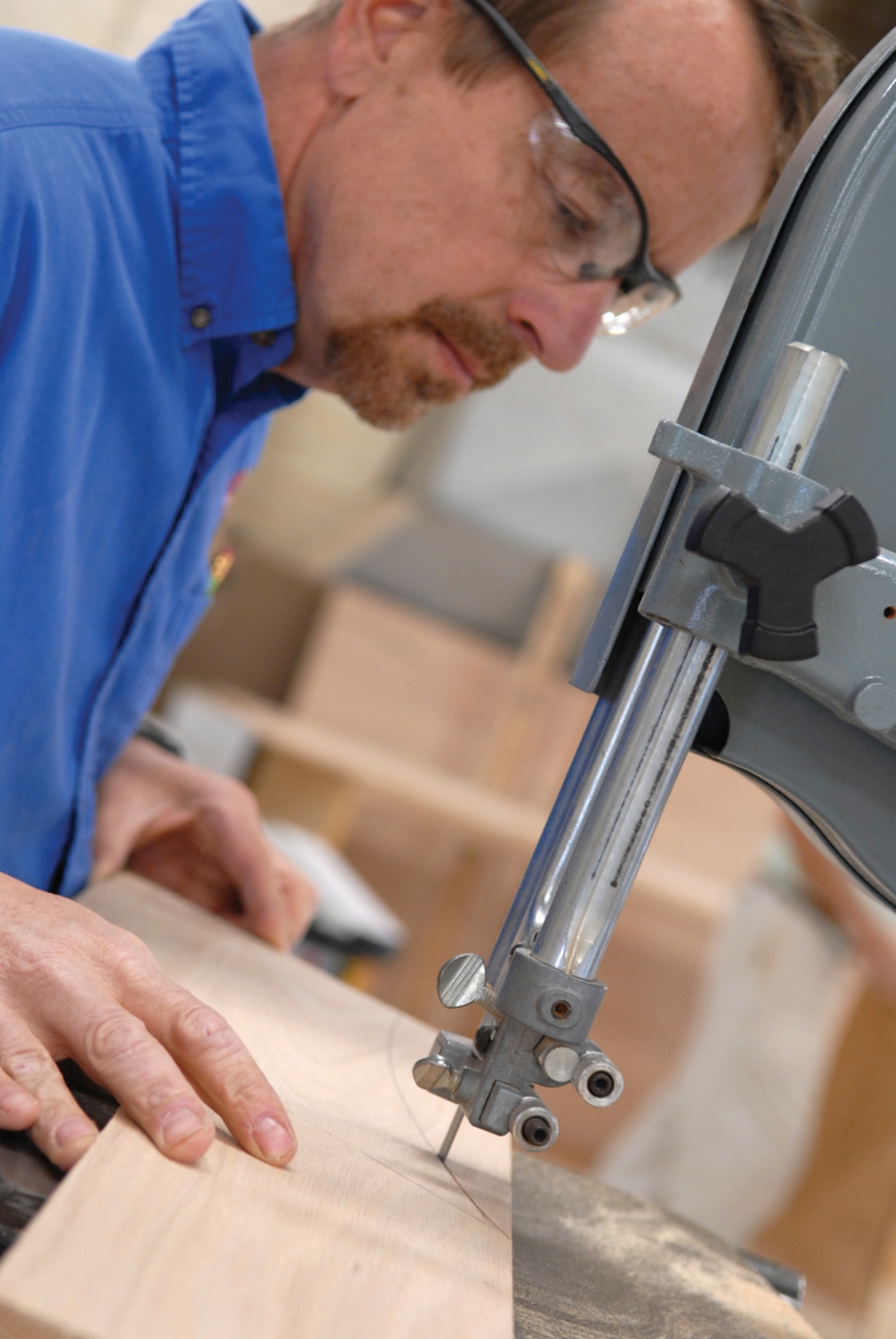 Retired Sailor Barry Richardson, part-time wood crafter at the Luke Air Force Base Wood Hobby Shop, cuts pieces for a chief’s shadow box on a ban saw at the shop on March 30. 
“If people come in and want a particular shadow box, we will make it for them,” Mr. Richardson said, who works about 20 hours a week. (photo/ Deborah Silliman Wolfe)