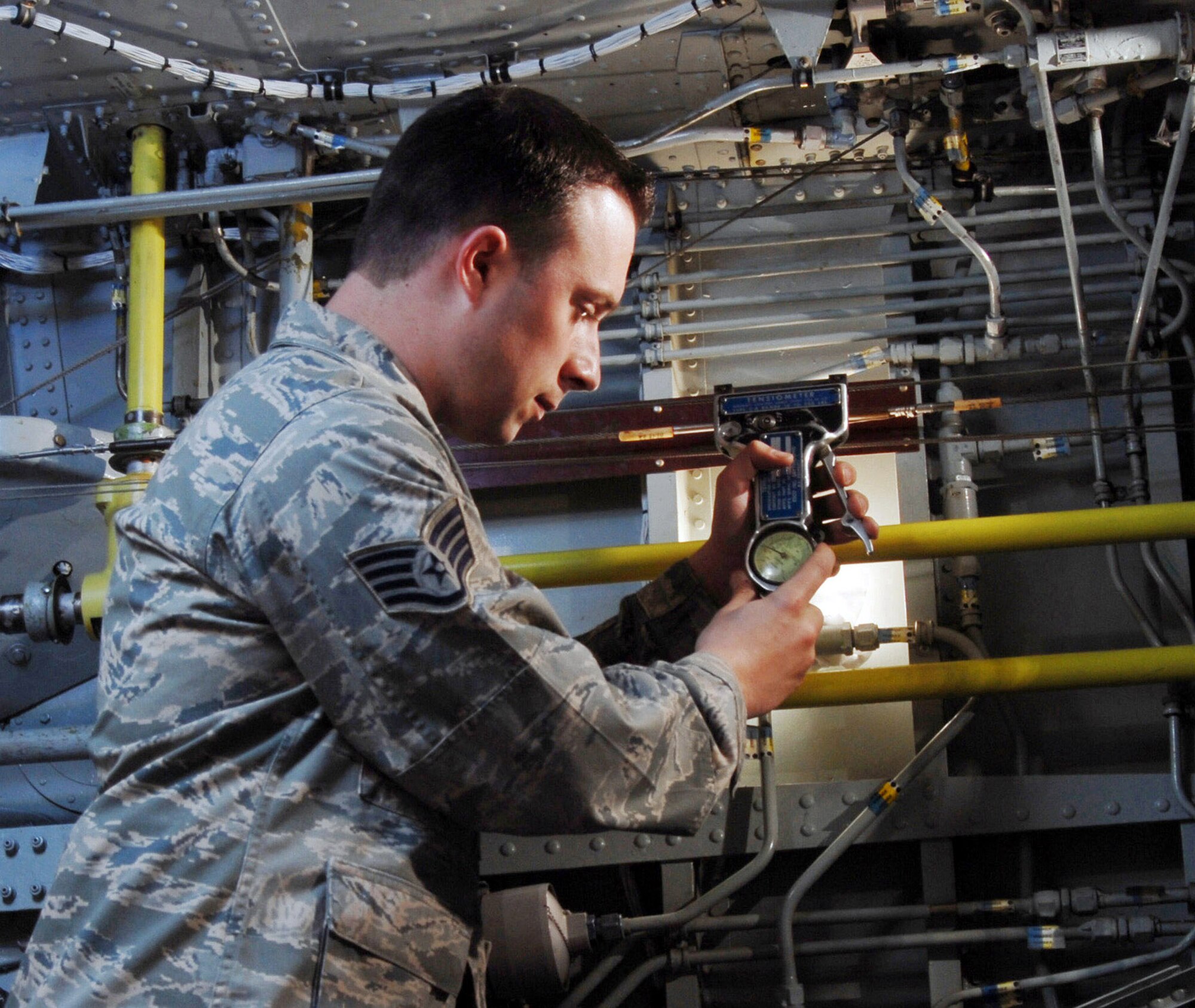 Staff Sgt. Greg Thompson uses a cable tension meter to check an aileron cable inside the main landing gear wheel well on an KC-135 Stratotanker at March Air Reserve Base, Calif. He is an aircraft mechanic assigned to the 452nd Maintenance Squadron's Aero Repair Section. (U.S. Air Force photo/Val Gempis)