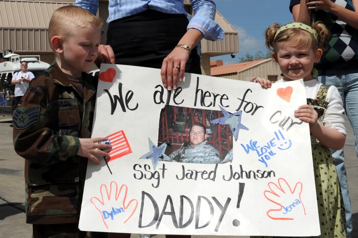 SSgt Jared Johnson's, 99 Security Forces Squadron, children, Dylan and Jenna Johnson hold a poster in support of their father for the arrival of the  deployed airman from the 99th SFS at Nellis AFB,Nev., 1 April. The 130 security forces Airmen will arrive home from an eight-month deployment, which included serving on missions such as convoy security detail, installation security and patrol duty in Iraq. (U.S. Air Force photo by Airman 1st Class Brett Clashman/Released)