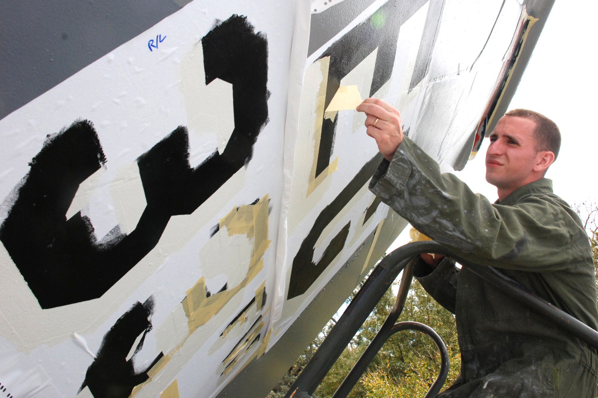 EGLIN AIR FORCE BASE, Fla. -- Senior Airman Curtis Deleon, 33rd Maintenance Squadron corrosion section, removes masking tape after stenciling the left vertical stabilizer of an F-15 Eagle static display on Eglin Blvd. March 24. He and nine other Airmen began the restoration process by scraping, sanding and washing the outer surface of the aircraft. The aircraft was then coated with more than 34 gallons of primer and paint with a life expectancy of 10 years. (U.S. Air Force photo by Staff Sgt. Mike Meares)  
