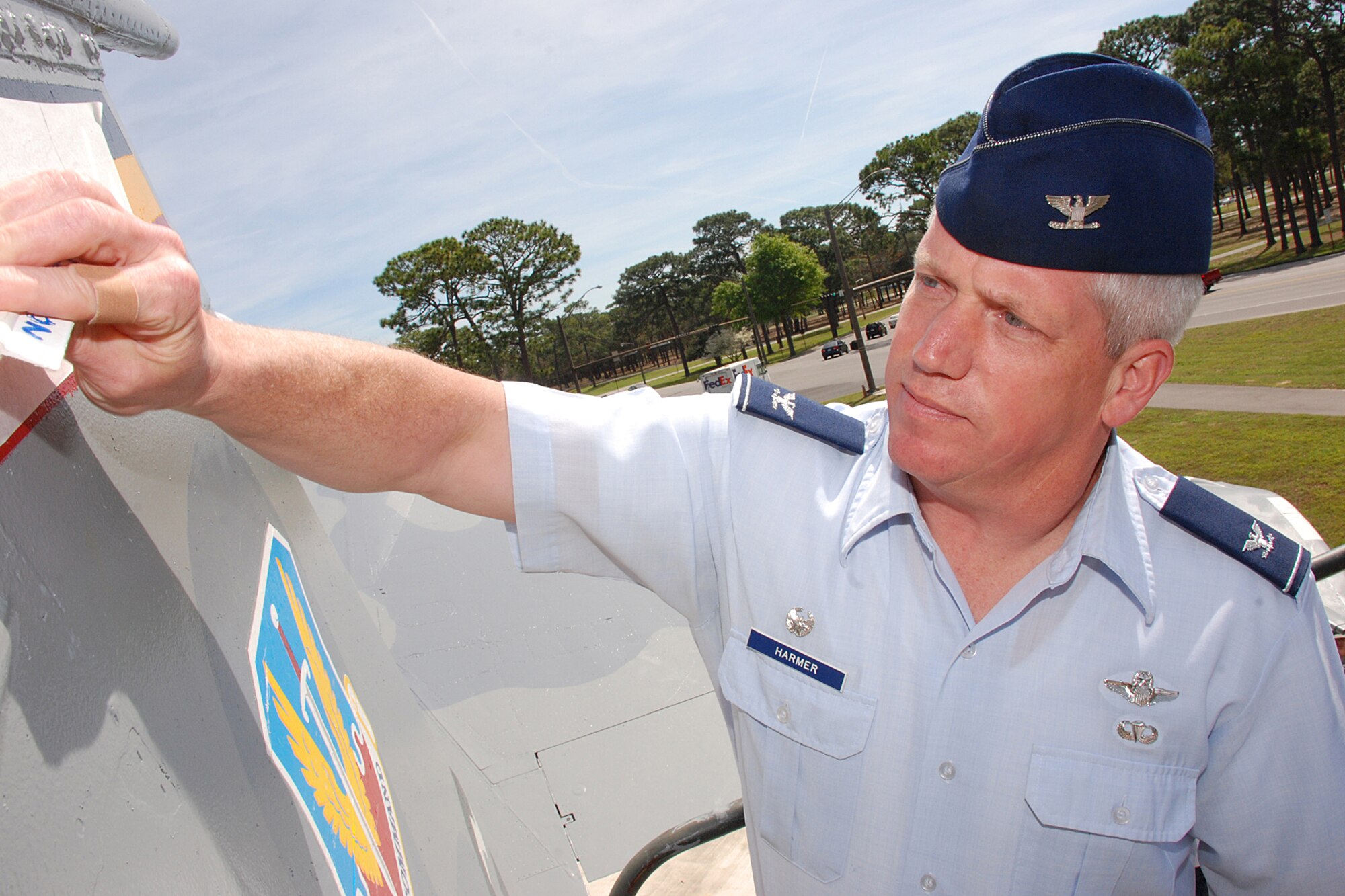 EGLIN AIR FORCE BASE, Fla. -- Col. Todd Harmer, 33rd Fighter Wing commander, places the final decal, "Nomads," on the right vertical stabilizer of the F-15 Eagle static display on Eglin Blvd., March 30. Nine Airmen from the 33rd Maintenance Squadron corrosion section took on the project to fully restore the aircraft. They coated it with more than 34 gallons of primer and paint; replaced the decals and stenciled the lettering. The aircraft stands as a visual testament of the men and women who have served the 33rd FW. (U.S. Air Force photo/Staff Sgt. Mike Meares)  