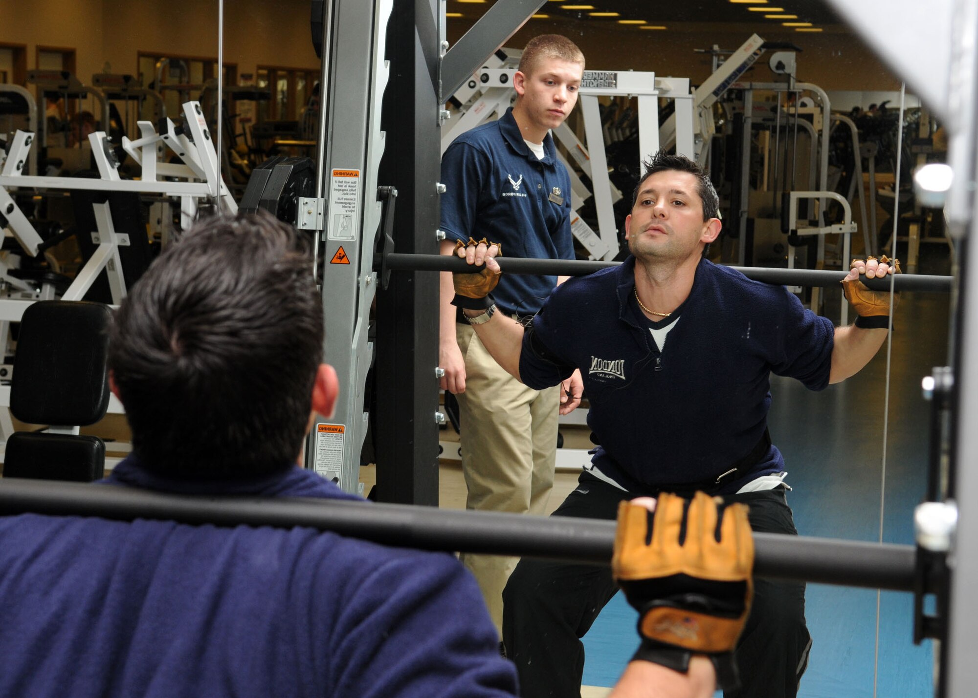Airman 1st Class Corey Rollins, 100th Force Support Squadron fitness specialist, ensures that Salvatore Grasso executes the proper squat technique during his workout at the Hardstand Gym April 1, 2009, at RAF Mildenhall, England. Airman Rollins is trained to observe and advise individuals of proper technique to avoid injury. (U.S. Air Force photo by Staff Sgt. Jerry Fleshman) 