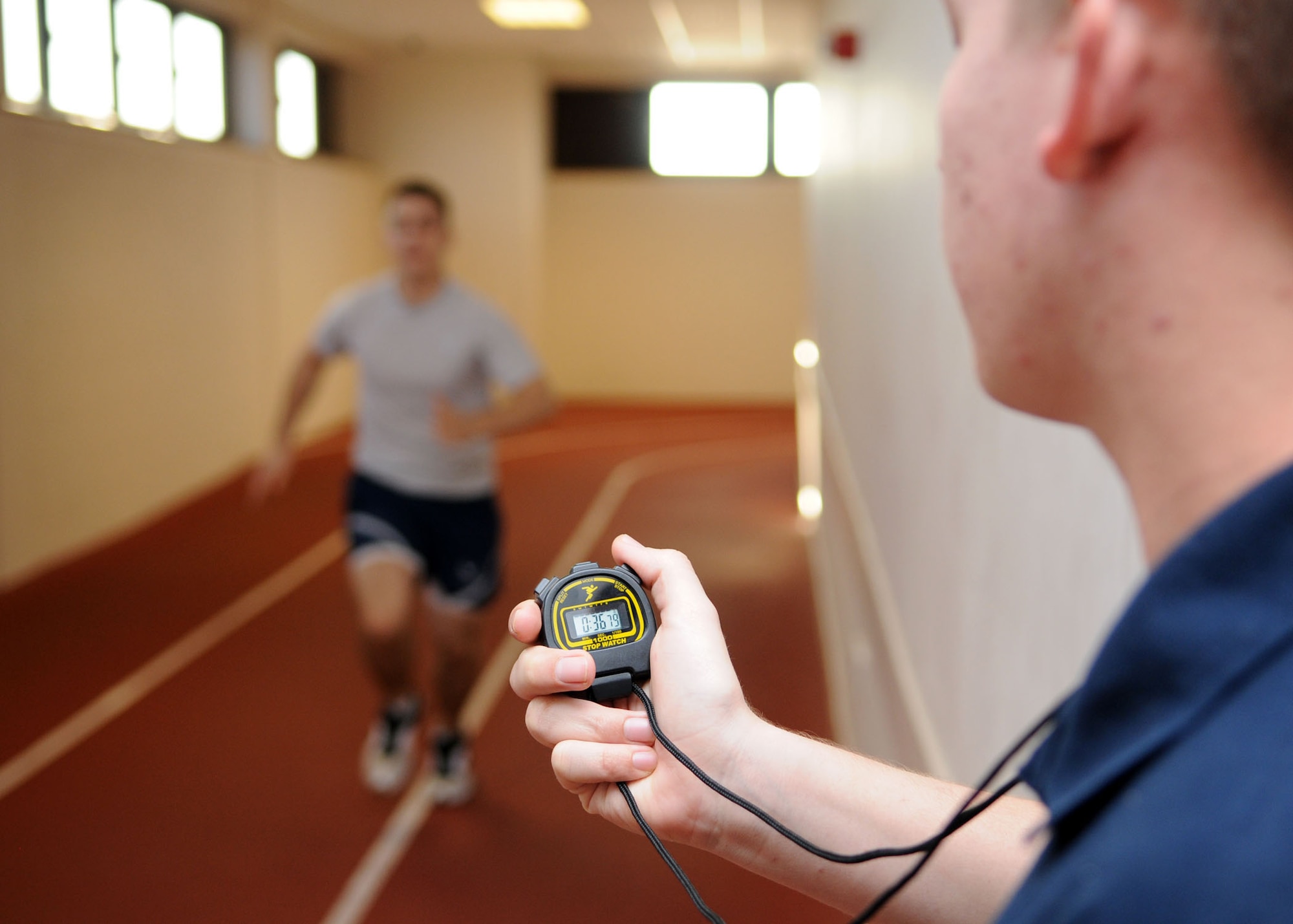 Airman 1st Class Corey Rollins, 100th Force Support Squadron fitness specialist, times Senior Airman Blaque Kuchel of the 100th Logistics Readiness Squadron during his mile-and-a-half run inside the Hardstand Gym’s indoor track April 1, 2009, at RAF Mildenhall, England. Airmen Rollins assists Airman in many areas of physical fitness by offering them advice to improve overall fitness. (U.S. Air Force photo by Staff Sgt. Jerry Fleshman)