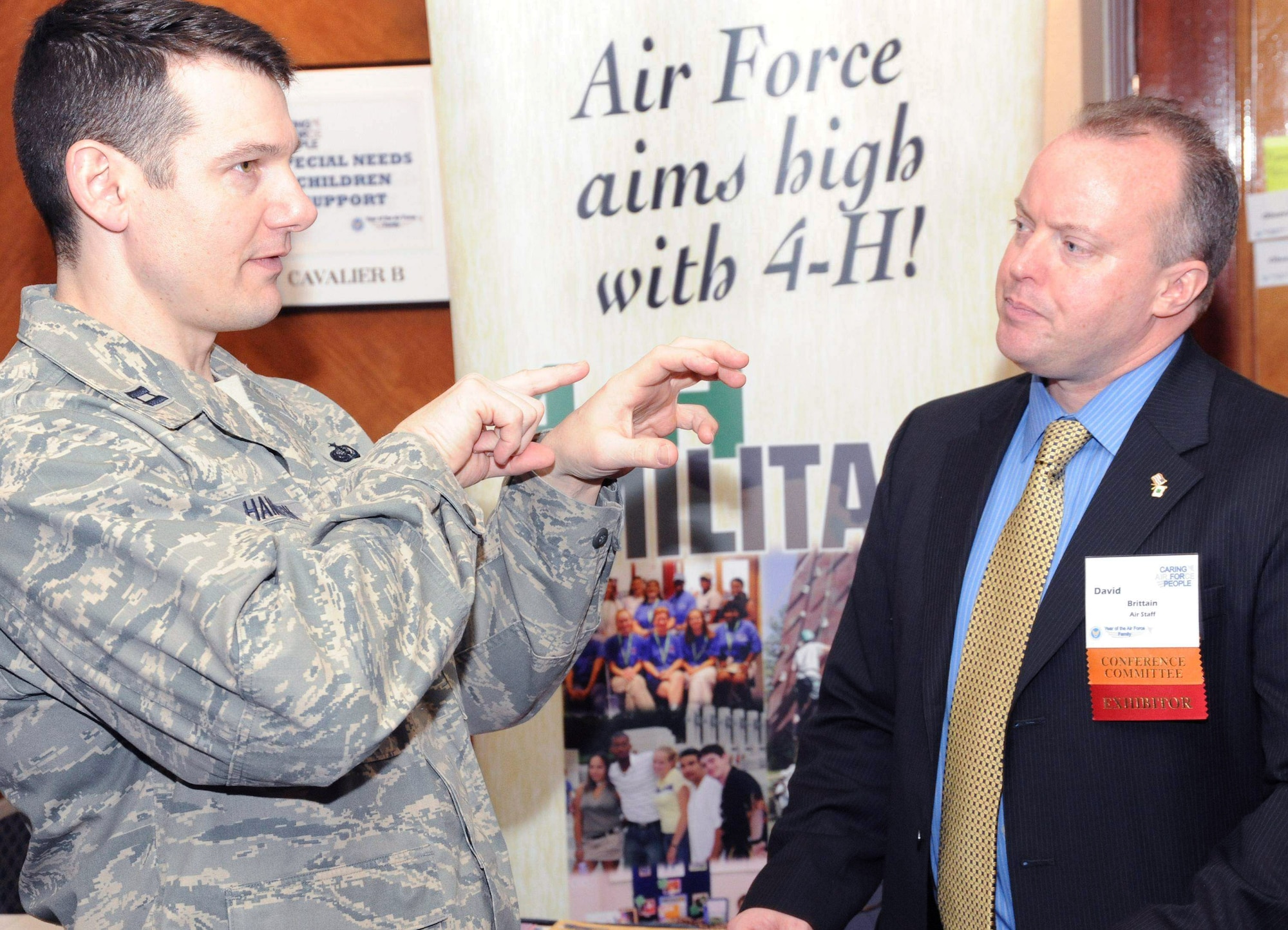 Captain Charles Hamilton speaks with David Brittian about 4-H opportunities offered to military youth during the Year of the Air Force Family: Caring for People Forum April 1 at Arlington, Va. Mr. Brittian said 4-H offers opportunities at Air Force bases worldwide and can be found at base youth centers or with school-age programs. Mr. Brittian is a youth development specialist with North Carolina State University. Captain Hamilton is the deputy chief of future operations at the Pentagon Services Division in Arlington. (U.S. Air Force photo/Staff Sgt. Patrick Brown) 
