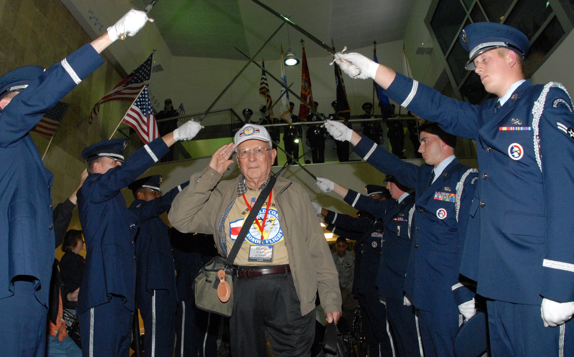 A World War II veteran salutes as he passes under the Honor Guard saber team upon returning from the 3rd annual Honor Flight April 1.  The veterans left Florida in the morning to spend the day in Washington and visit the World War II memorial before returning to a hero’s welcome.  More than 200 military members lined the concourse to greet the veterans and their family as they exited.  Children and adults greeted them with flags and signs while bands played.  U.S. Air Force photo/ Samuel King Jr.