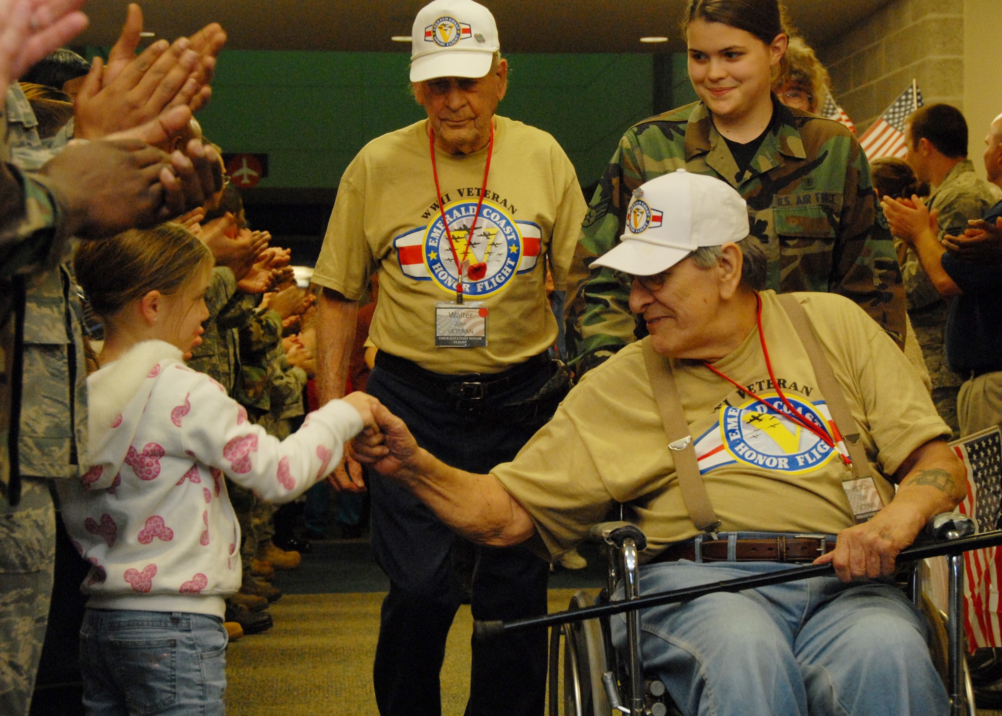 A veteran stops to greet a little girl in the extended receiving line upon returning from the 3rd annual Honor Flight April 1.  The veterans left Florida in the morning to spend the day in Washington and visit the World War II memorial before returning to a hero’s welcome.  More than 200 military members lined the concourse to greet the veterans and their family as they exited.  Children and adults greeted them with flags and signs while bands played.  U.S. Air Force photo/ Samuel King Jr.