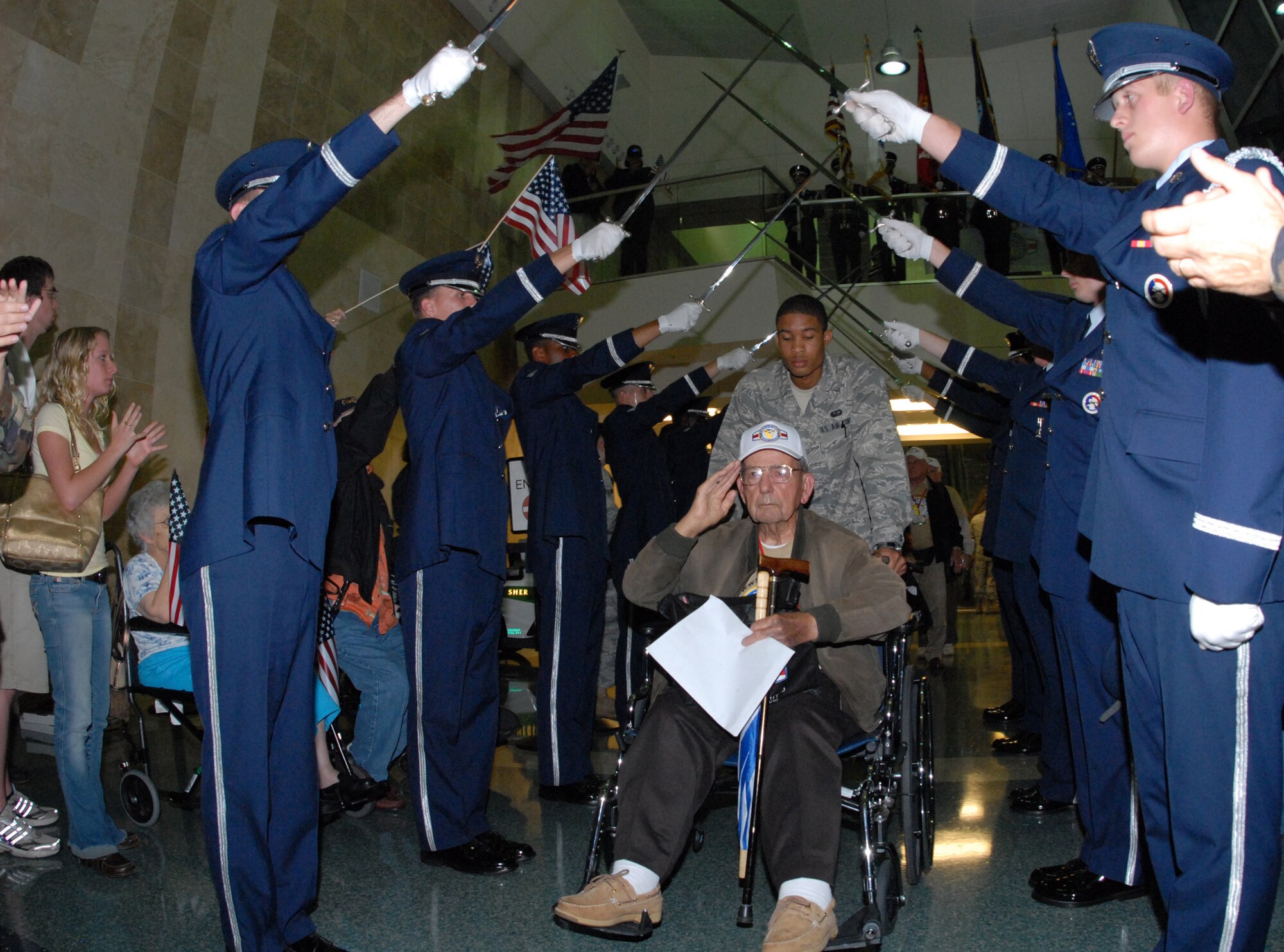A World War II veteran salutes as he passes under the Honor Guard saber team upon returning from the 3rd annual Honor Flight April 1.  The veterans left Florida in the morning to spend the day in Washington and visit the World War II memorial before returning to a hero’s welcome.  More than 200 military members lined the concourse to greet the veterans and their family as they exited.  Children and adults greeted them with flags and signs while bands played.  U.S. Air Force photo/ Samuel King Jr.