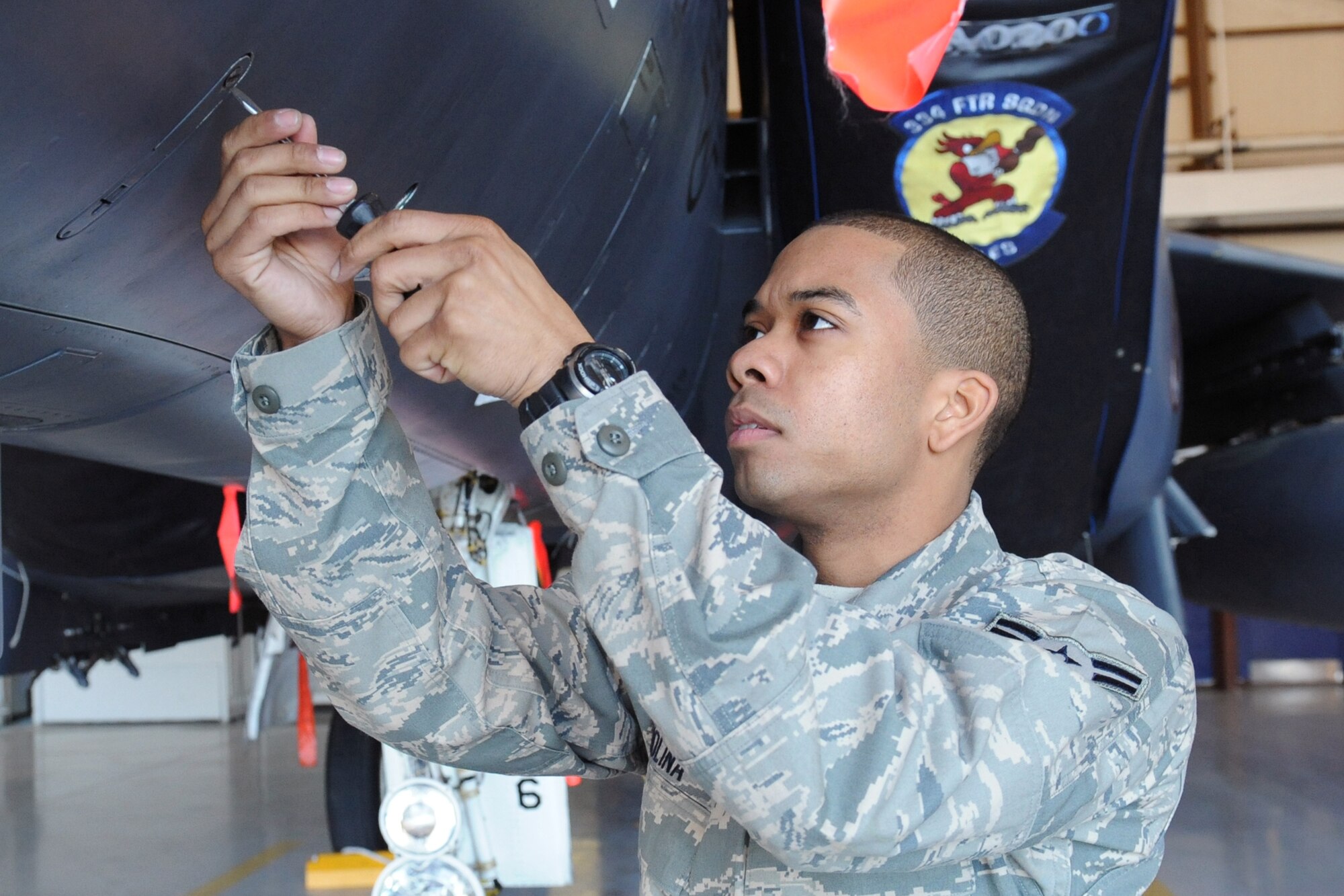 Airman 1st Class Julian Molina, 4th Component Maintenance Squadron, unscrews a panel on an F-15E Strike Eagle in a hangar near the flightline at Seymour Johnson Air Force Base, N.C., March 30, 2009. Airman Molina, a fuels system technician, opens the panel to perform a safety inspection.  (U.S. Air Force photo by Airman 1st Class Whitney S. Lambert)