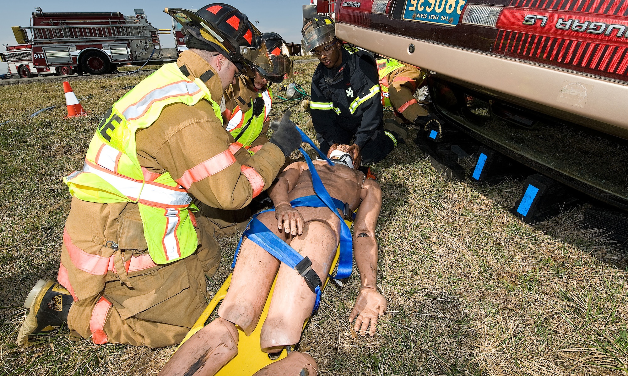 436th Civil Engineer Squadron firefighters and an ambulance response team member straps down the dummy to administer first aid during auto extrication exercise. (U.S. Air Force photo/ Roland Balik)