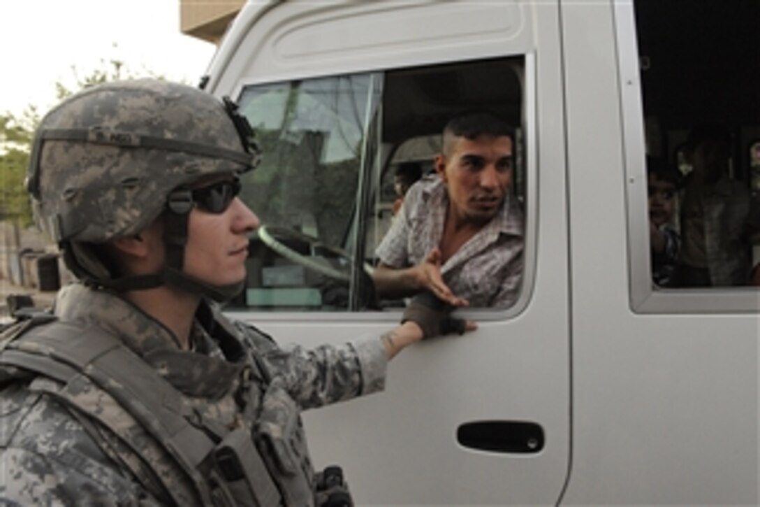 U.S. Army Sgt. Justin Parks and others from 3rd Battalion, 5th Cavalry Regiment, 1st Cavalry Division question a bus driver while patrolling through a market near Joint Security Station War Eagle in Baghdad, Iraq, on March 16, 2009.  