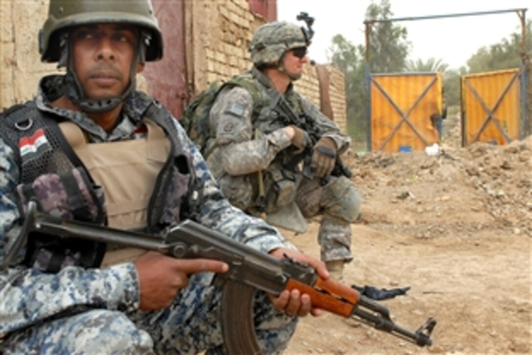 U.S. Army Spc. Michael Ingles, right, and an Iraqi national policeman and take a break from searching houses during Operation Bull Chisel in Baghdad, Iraq, March 30, 2009. Ingles is a cannon crewmember assigned to the 1st Battalion, 319th Airborne Field Artillery Regiment.