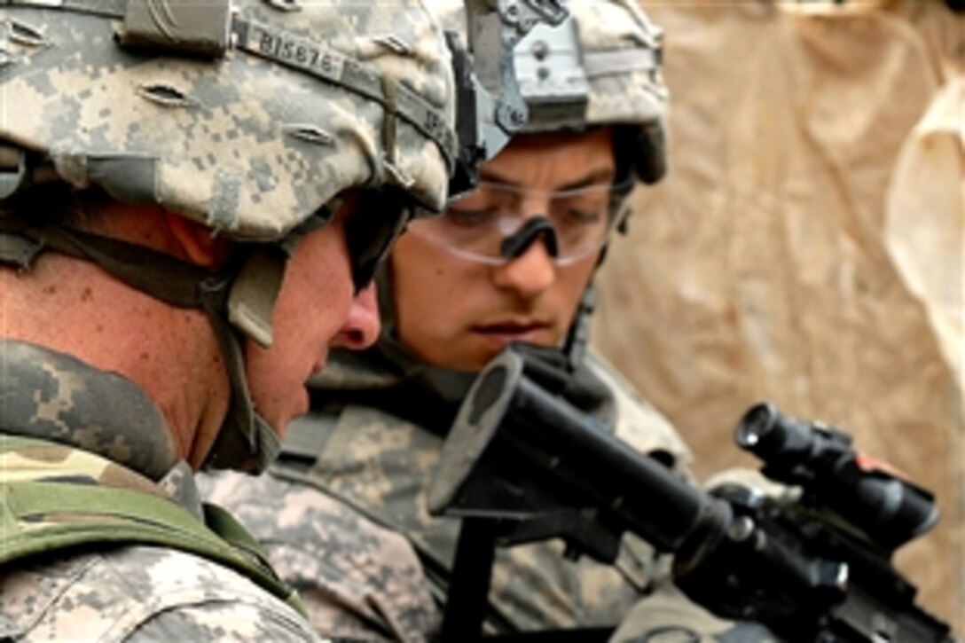U.S. Army Spc. Michael Ingles, foreground, and Spc. Martin Aguilar check an identification card during Operation Bull Chisel in Baghdad, Iraq, March 30, 2009. Both are cannon crewmembers assigned to the 1st Battalion, 319th Airborne Field Artillery Regiment.
