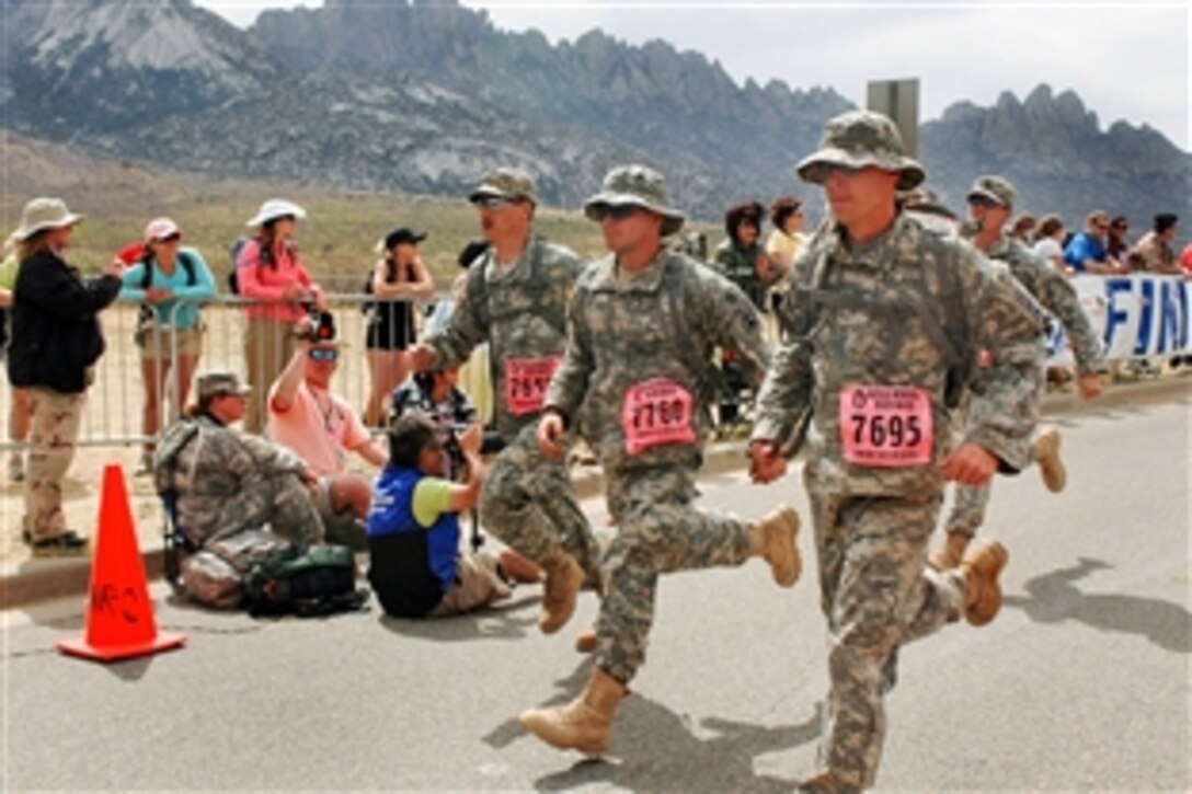Three soldiers cross the finish line together less than seven hours after they began the 20th Annual Bataan Memorial Death March marathon at White Sands Missile Range, N.M., March 29, 2009. From left to right: 1st Lt. Kelsey Erickson, Pfc. Chris Wolf and Spc. Scott Meeds. The soldiers are assigned to Company A, 1st Battalion, 128th Infantry Regiment, 32nd Infantry Brigade Combat Team.