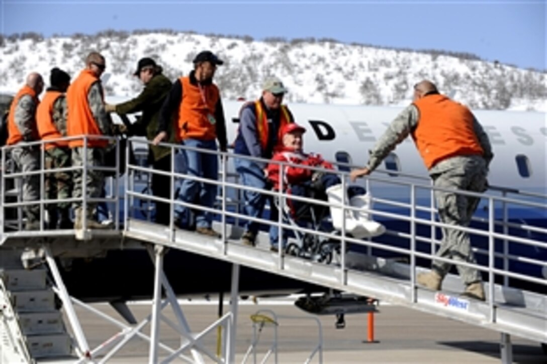 Steve Slater escorts Russell Worth off an aircraft at the Aspen Airport, Colo., March 28, 2009. Slater is a ski instructor for the Disabled American Veterans Winter Sports Clinic. This is Worth's sixteenth year attending the Disabled American Veterans Winter Sports Clinic, which is the world leader in promoting rehabilitation by instructing veterans with disabilities in adaptive Alpine and Nordic skiing.