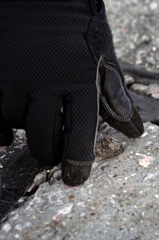 Airman 1st Class David Jack, 28th Civil Engineer Squadron emergency management apprentice, collects a piece of foreign object debris here, April 3. FOD walks are performed to clean the flight line of debris that can damage or disable aircraft. (U.S. Air Force photo/Senior Airman Marc I. Lane)