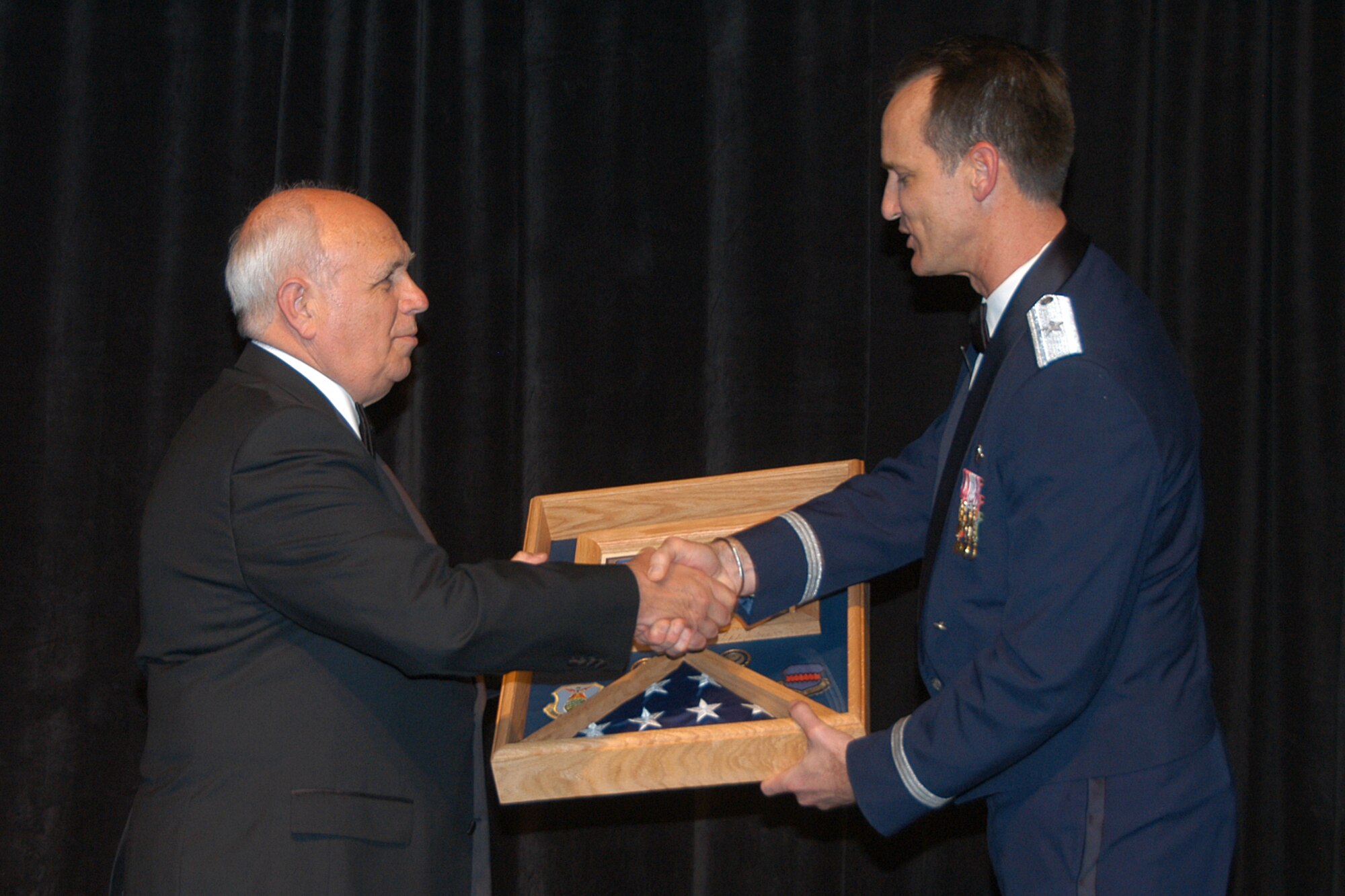 OFFUTT AIR FORCE BASE, Neb. -- Brig. Gen. James Jones, 55th Wing commander, presents an honorary shadow box to Dave Webber, master of ceremonies for the 55th Wing Birthday Ball at the Qwest Center March 28. He was presented the gift in appreciation for his tireless support of the 55th Wing and the local community. 
 Air Force Photo by Jeff Gates                                 