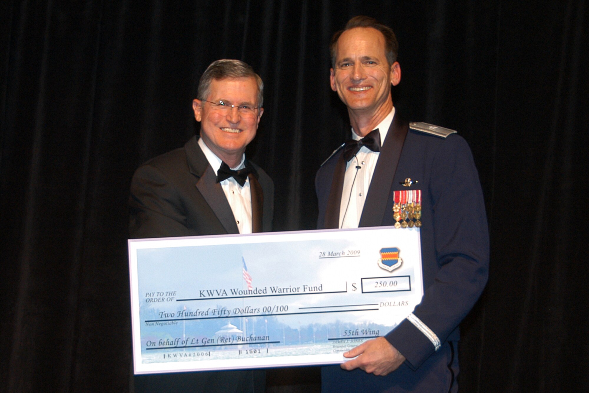 OFFUTT AIR FORCE BASE, Neb. -- Brig. Gen. James Jones, 55th Wing commander,  presents the event's guest speaker retired Lt. Gen. Walter E. Buchanan III with a donation check to the KWVA Wounded Warrior Fund during the 2009 Birthday Ball at the Qwest Center March 28. Air Force Photo by Jeff Gates                                