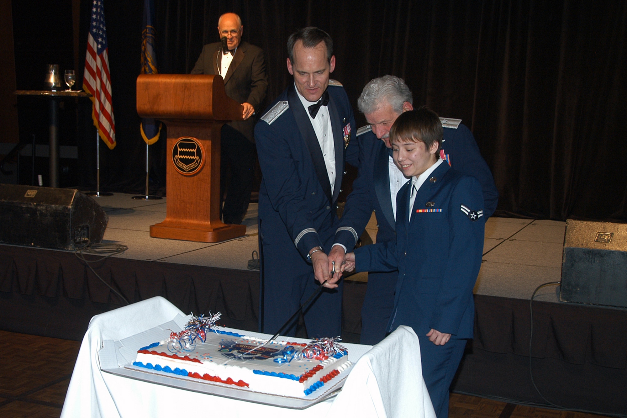 OFFUTT AIR FORCE BASE, Neb. -- Brig. Gen. James Jones, 55th Wing commander, retired Brig. Gen. Regis Urschler and Airman 1st Class Veronica Patton make the first cut in the traditional 55th Wing birthday cake. It is customary for a senior attendee and junior member to make the first cut. The 2009 Birthday Ball was held at the Qwest Center March 28. Air Force Photo by Jeff Gates                                      